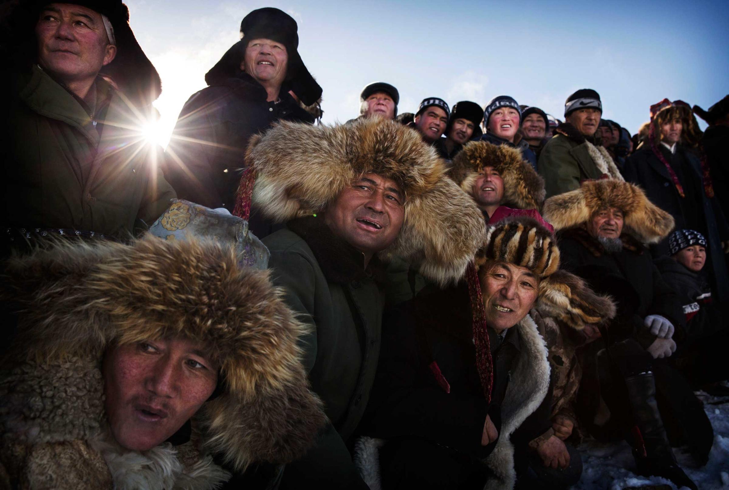 Professional People First Place. Eagle Hunters of Western China. Spectators react as they watch a Chinese Kazakh eagle hunter, not seen, release his bird during a local competition on January 30, 2015 in the mountains of Qinghe County, Xinjiang, northwestern China.