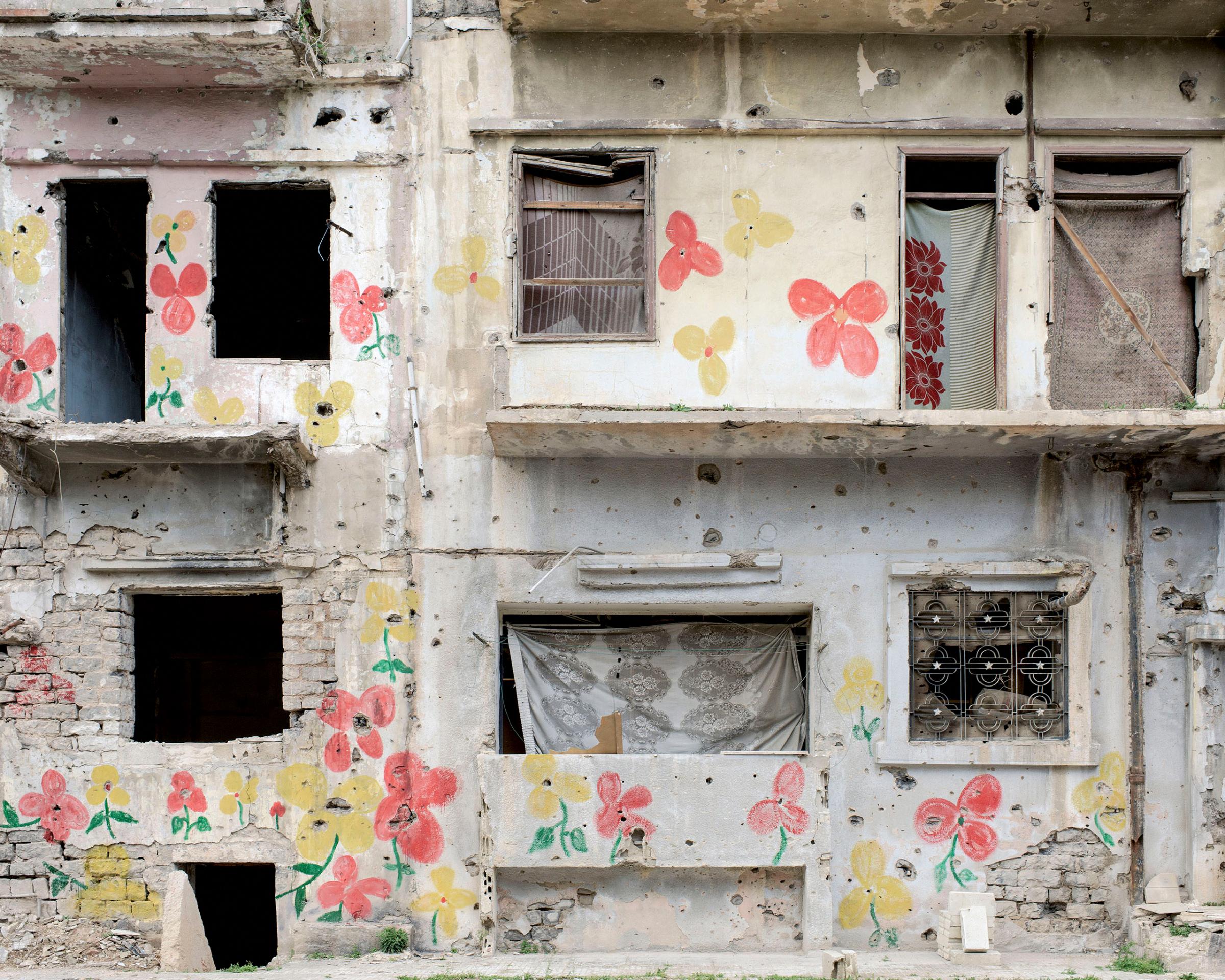 Paintings of flowers are seen on a destroyed building in Homs, Syria, March 2016.