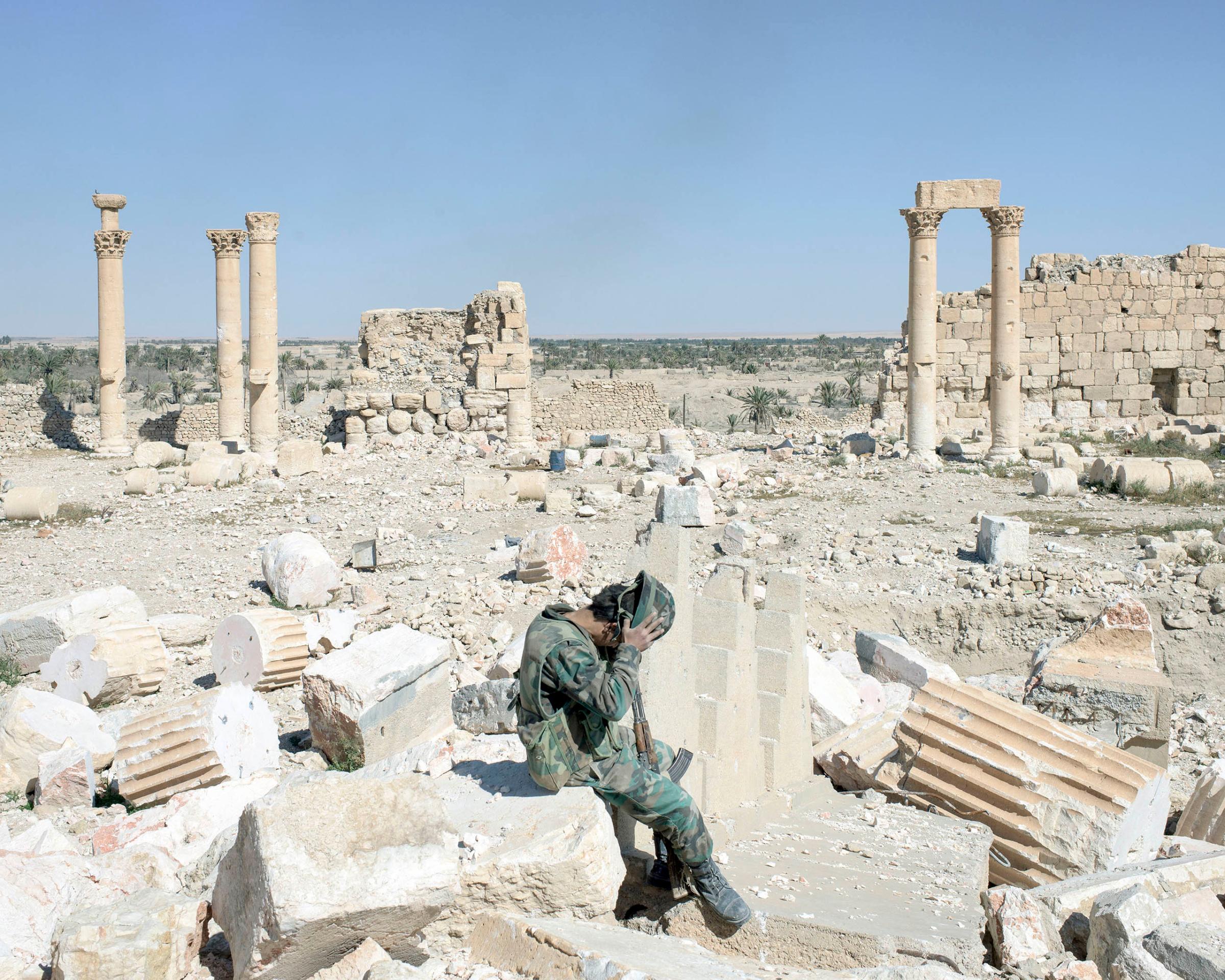A Syrian army soldier removes his helmet while sitting on rubble of the former Temple of Bel, one of several sites destroyed by ISIS militants, in ancient Palmyra, Syria, April 1, 2016.