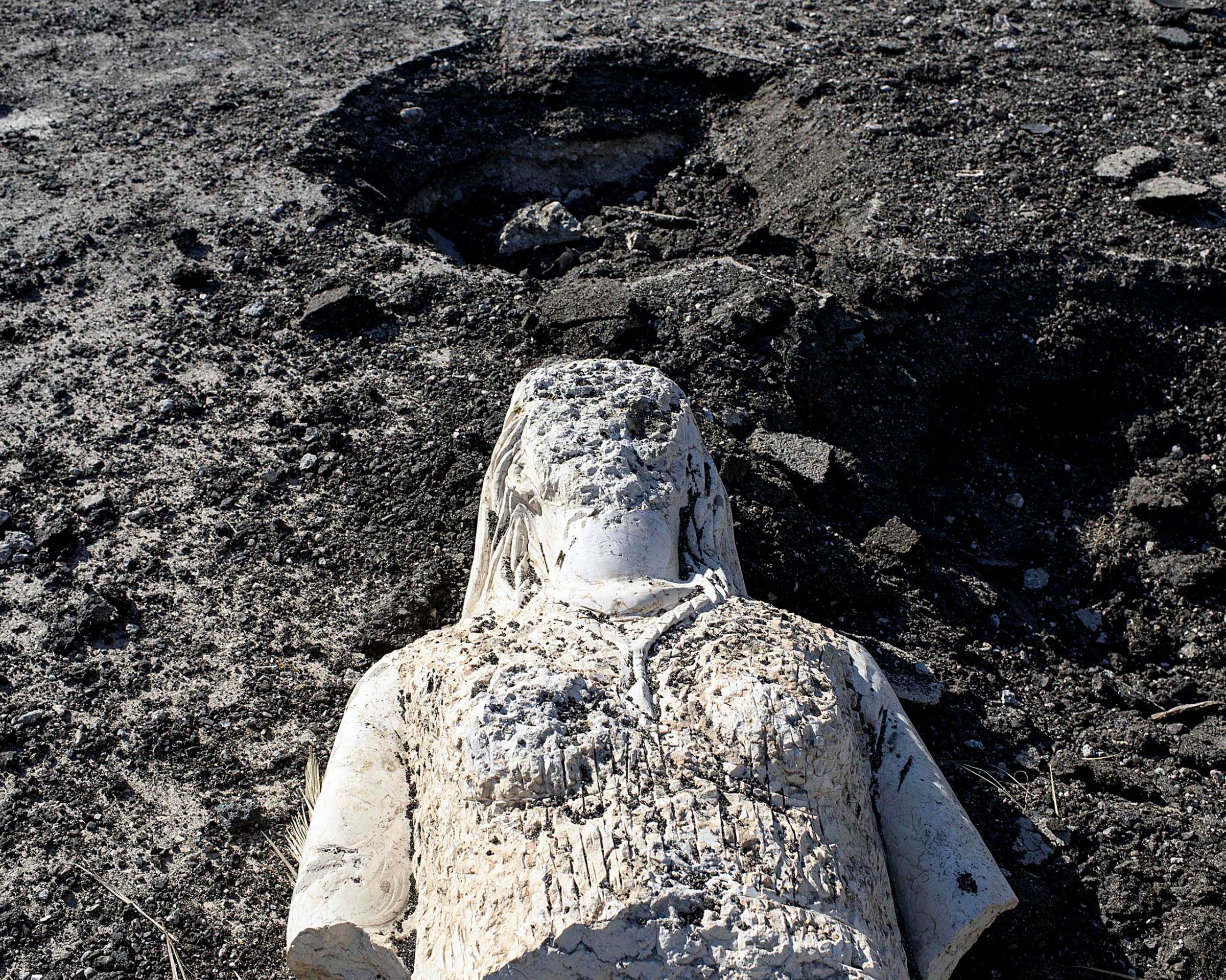 A defaced statue lies amongst holes left by the controlled detonation of mines planted by ISIS militants in central Palmyra, Syria, April 1, 2016.