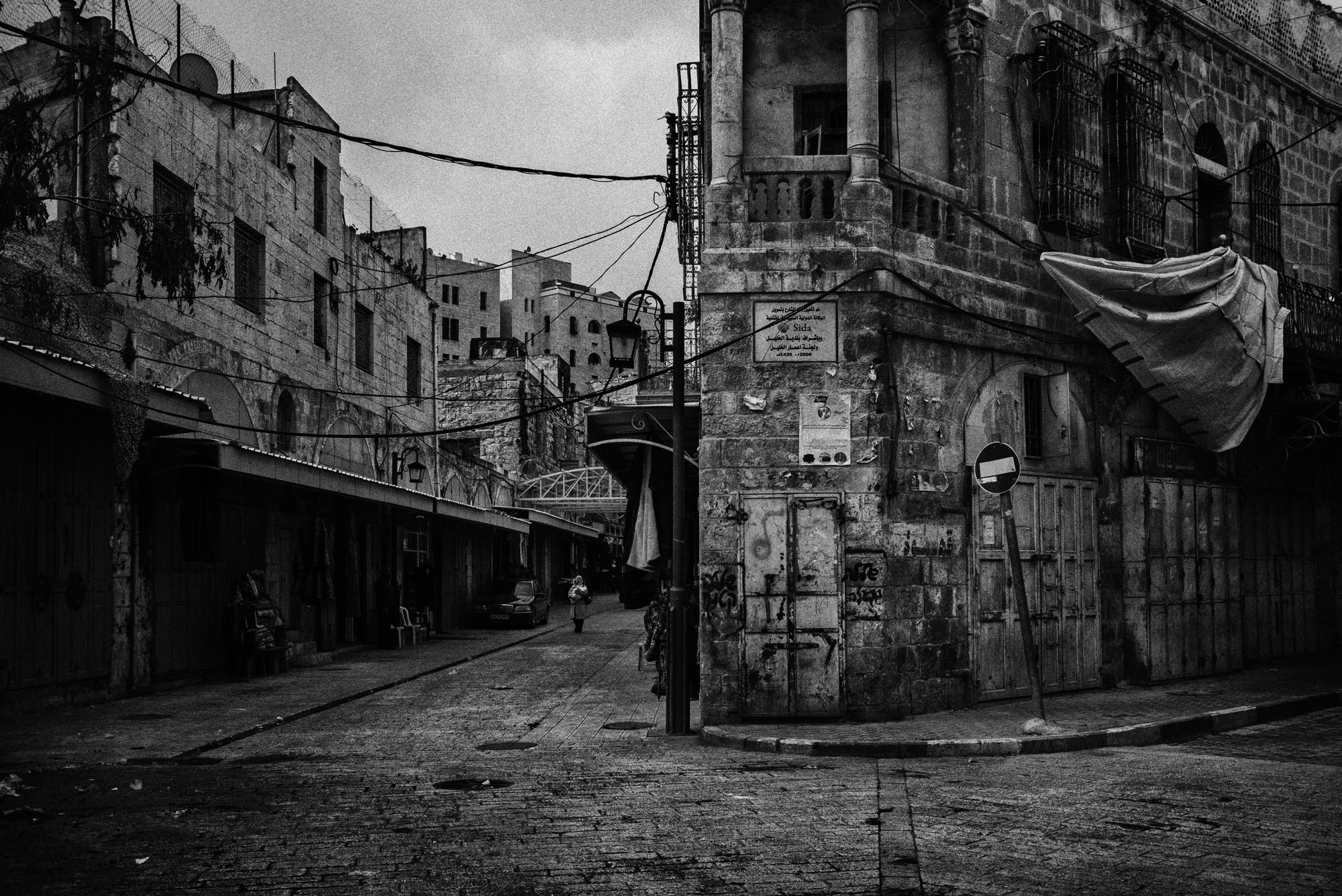 The homes of Jewish Israeli settlers can be seen on the left side of the road just over the closed shops in this area of Hebron's Old City, once a thriving market, November 2015.
