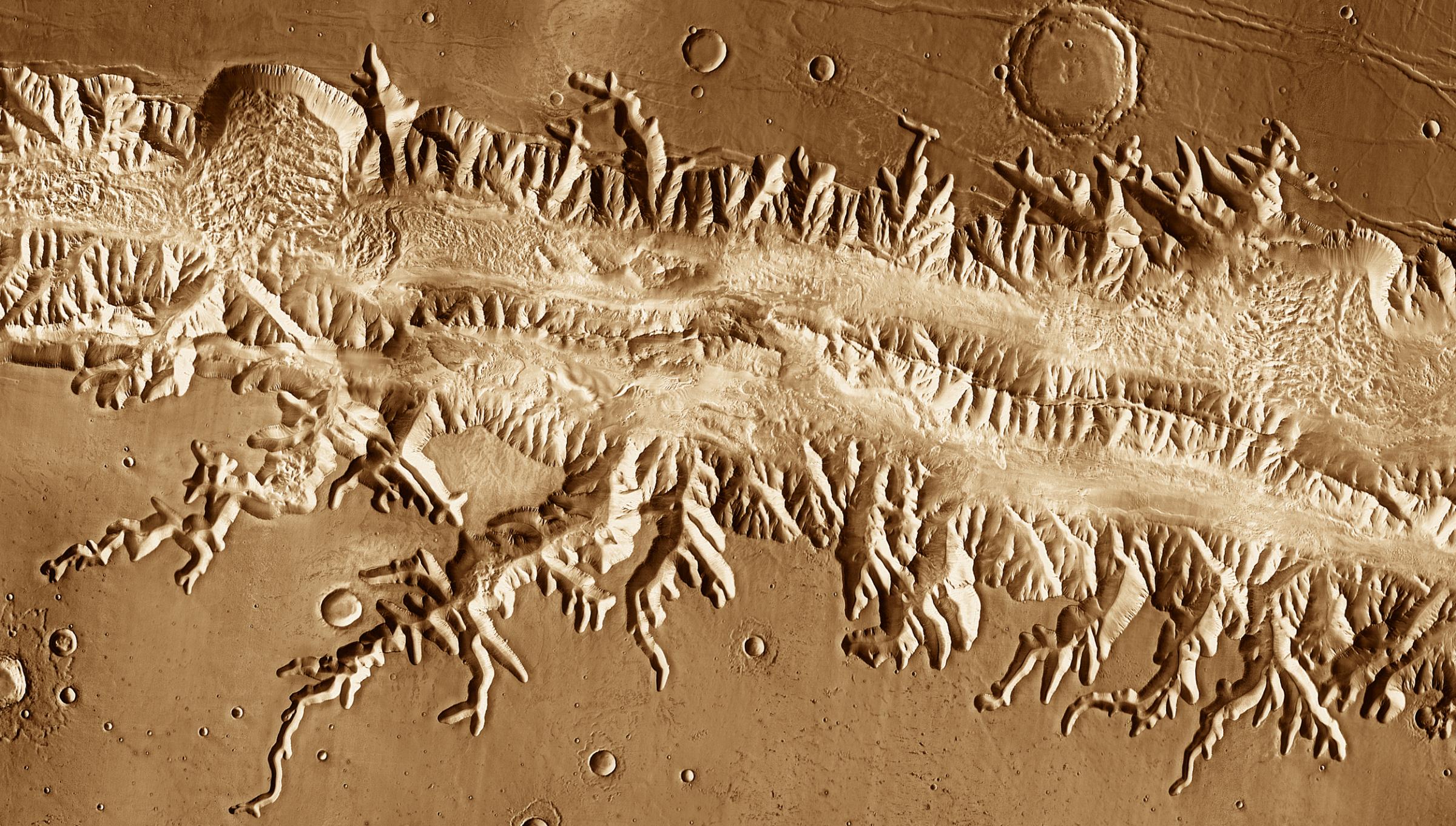 Valles Marineris: With a length great enough to stretch from New York to Los Angeles, Valles Marineris is the Grand Canyon of Mars. Scientists think the canyons cutting into the rim developed as subsurface water escaped and the ground collapsed, a process called "sapping." This image was acquired July 2005 by the Thermal Emission Imaging System instrument on NASA's Mars Odyssey orbiter.