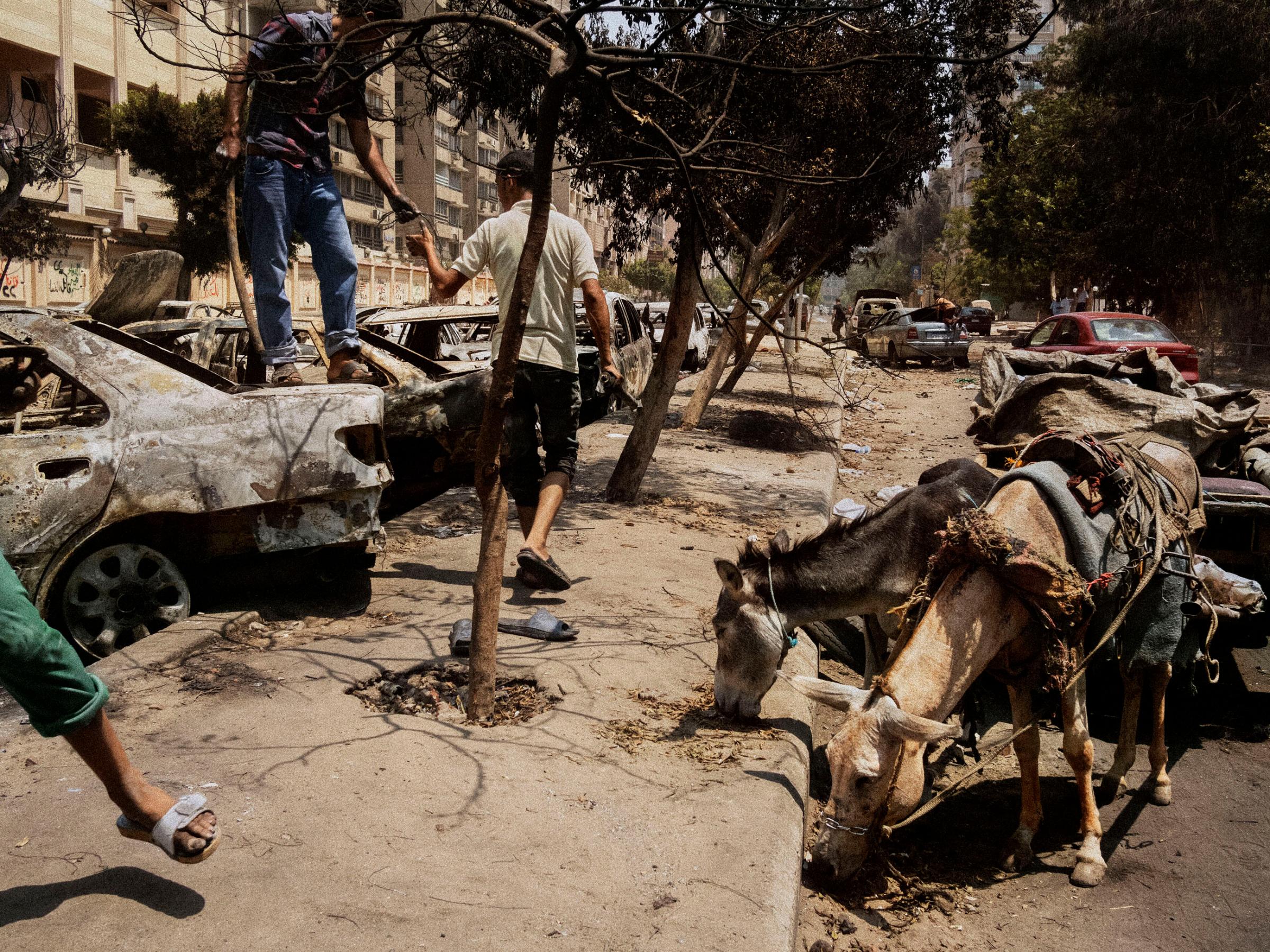 EGYPT. Cairo. 2013. Men collecting scrap metal from burned cars and debris next to the Rabaa al-Adawiya mosque in Nasr City, the site of a massacre against Muslim Brotherhood supporters at the hands of the Egyptian police and army.