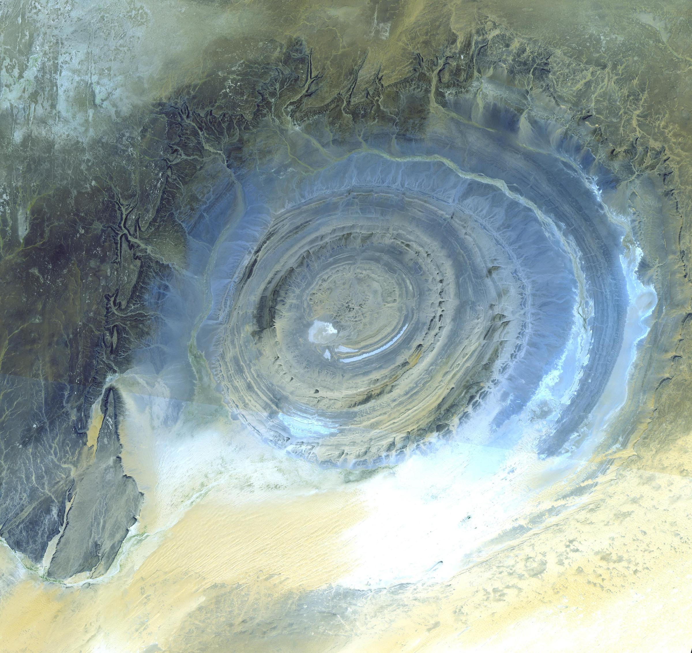 The Richat Structure, in the Sahara desert of Oudane, Mauritania has attracted attention since the earliest space missions because it forms a conspicuous bull's-eye in the otherwise rather featureless expanse. Initially interpreted as a meteorite impact structure because of its high degree of circularity, it is now thought to be merely a symmetrical uplift (circular anticline) that has been laid bare by erosion. The image was acquired Oct. 7, 2000.