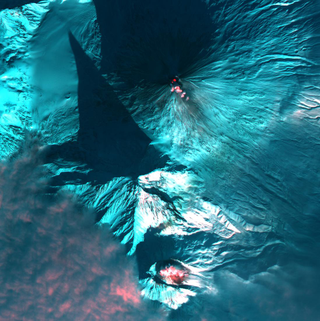 Red glows indicate the presence of heat from Bezymianny volcano (bottom) and Klyuchevskaya volcano (top) in Kamchatka, Russia acquired on Jan. 21, 2004.