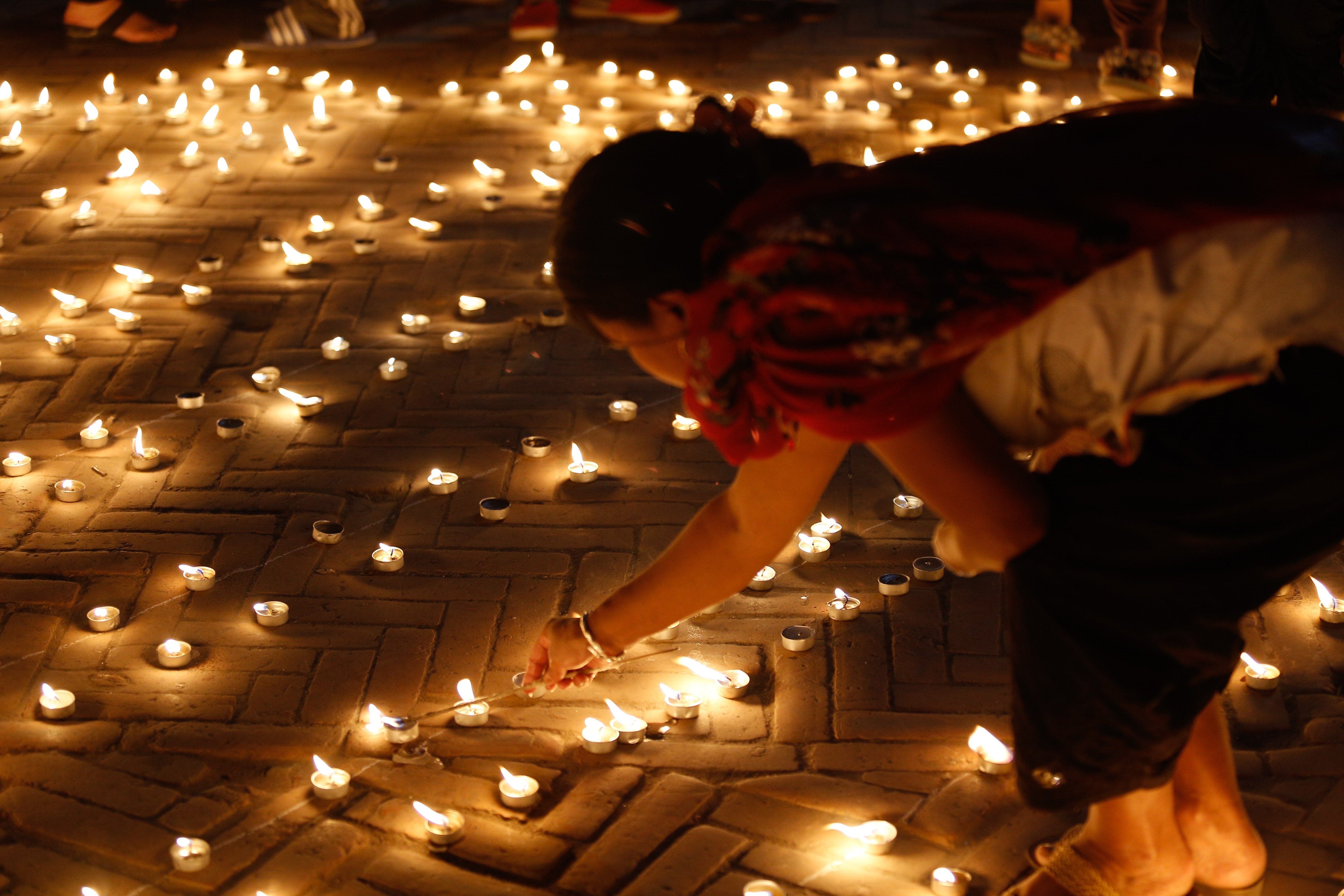 Nepalese woman lights a candle to pay homage to earthquake victims as they mark the 1st anniversary in Kathmandu, Nepal on April 24, 2016. (Anadolu Agency—Getty Images)