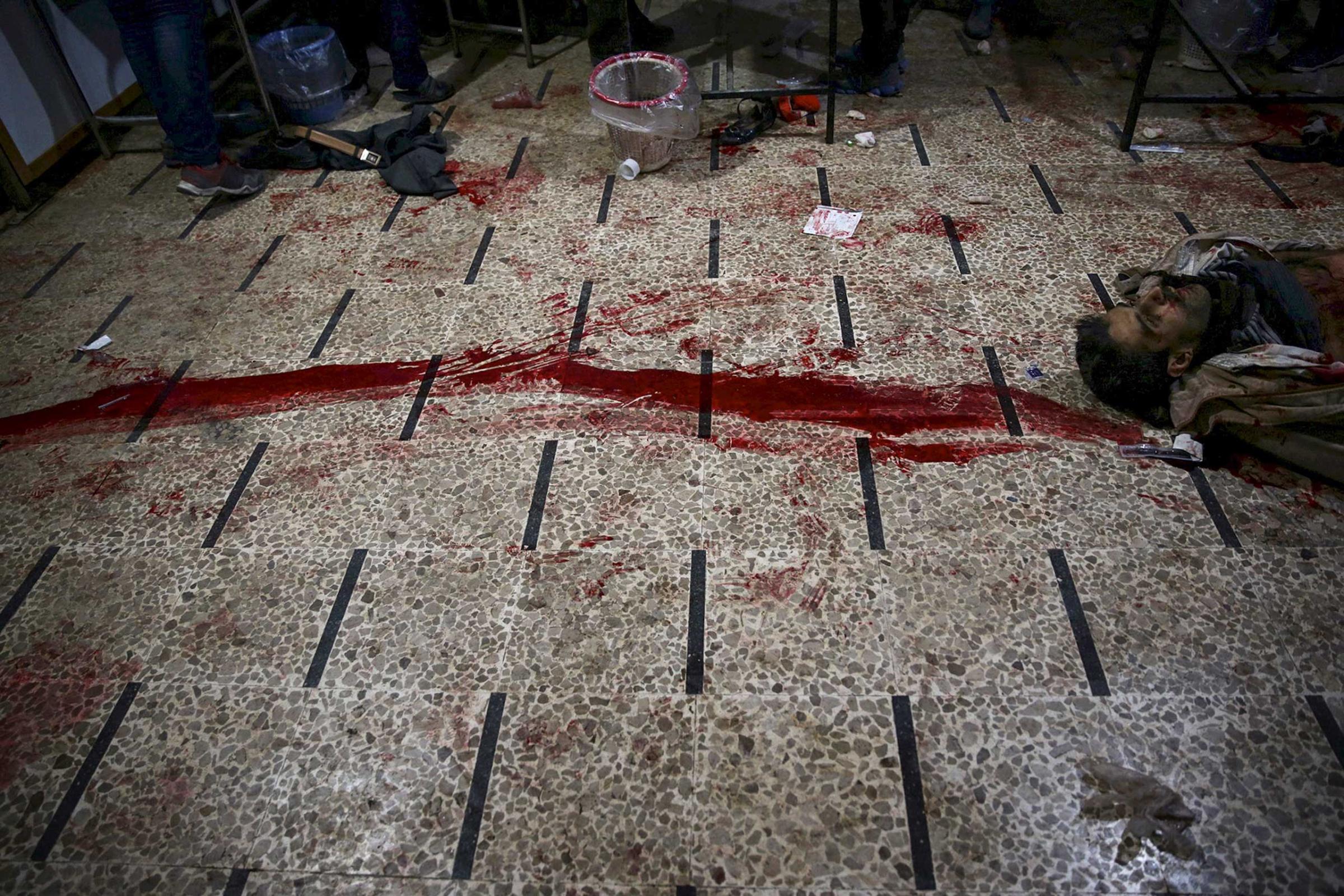 The body of a dead man is seen next to blood stains at a field hospital, after what activists said were air and missile strikes, in the Douma neighborhood of Damascus, Syria, Dec. 13, 2015.