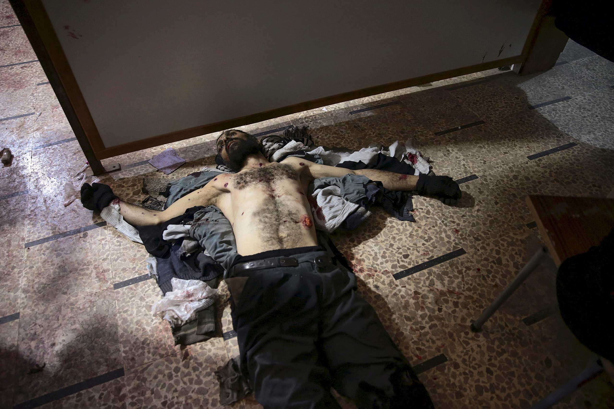 The body of a dead man is seen lying on the floor inside a field hospital after what activists said were air and missile strikes in the Douma neighborhood of Damascus, Syria, Dec. 13, 2015.