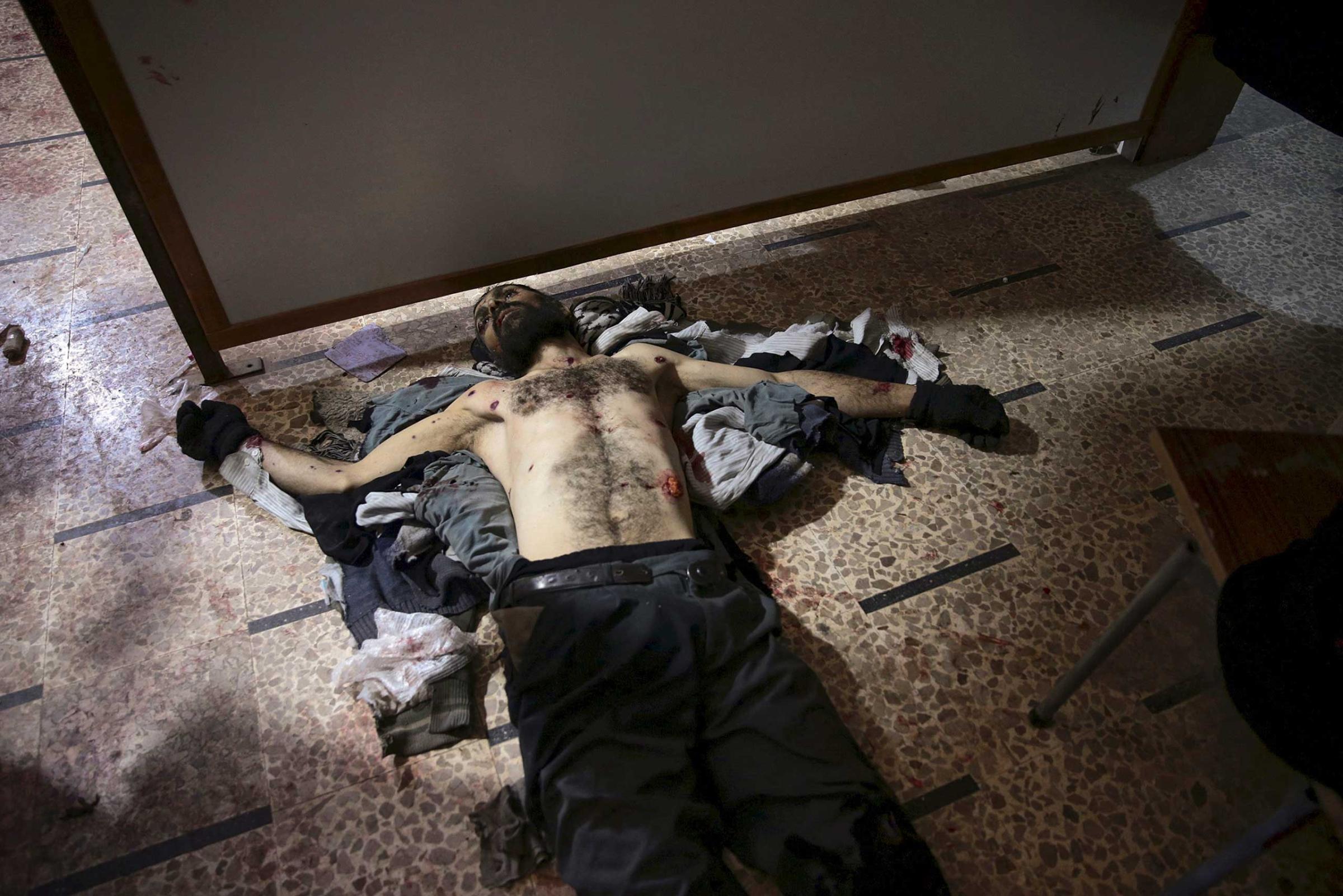 The body of a dead man is seen lying on the floor inside a field hospital after what activists said were air and missile strikes in the Douma neighborhood of Damascus, Syria December 13, 2015.
