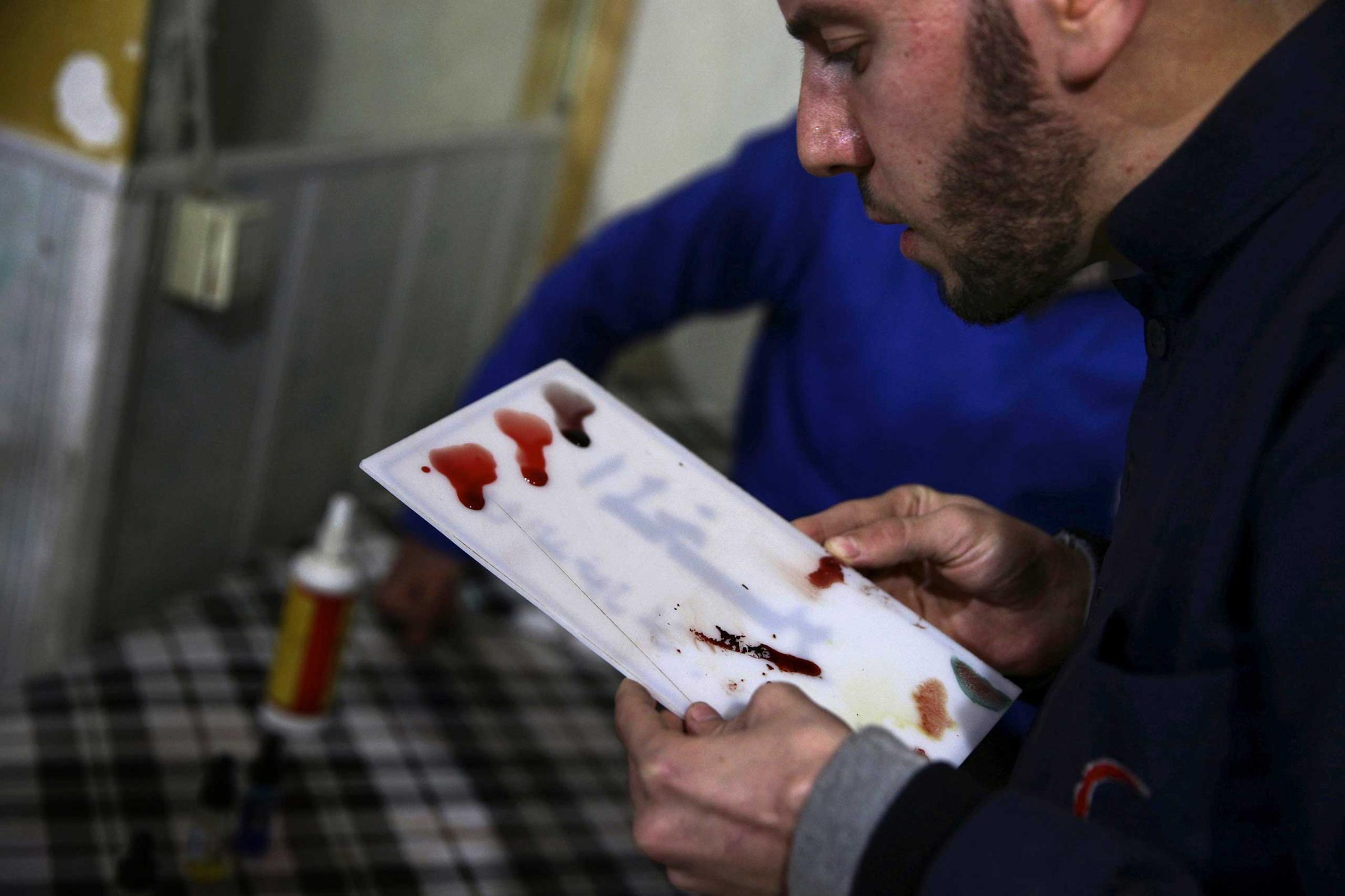 A medic tests patients' blood inside a field hospital in the Douma neighborhood of Damascus, Syria December 5, 2015.