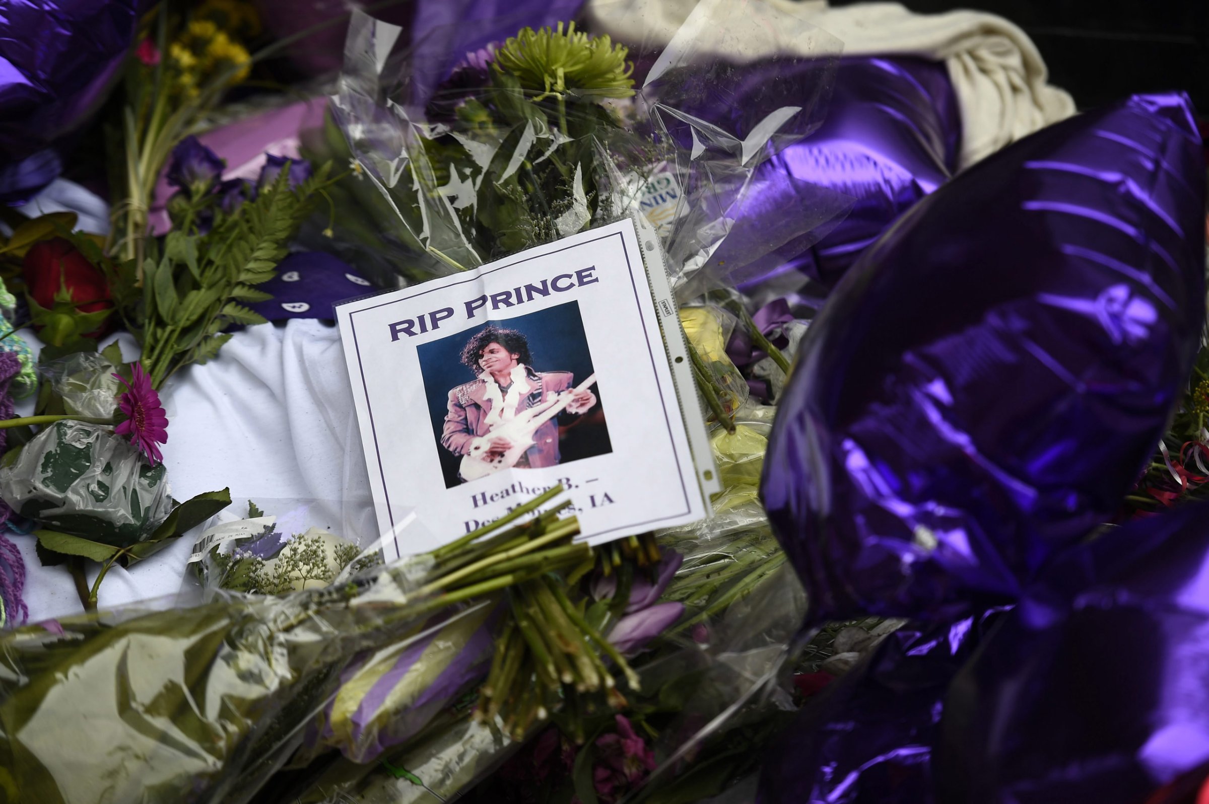 epa05272572 Fans leave flowers, photographs and balloons to a makeshift memorial under a star bearing Prince's name on an outside wall of First Avenue, the nightclub where Prince got his start, in Minneapolis, Minnesota, USA, 22 April 2016. US singer-songwriter and musician Prince died on 21 April at his residence in Chanhassen, Minnesota. He was 57. EPA/CRAIG LASSIG