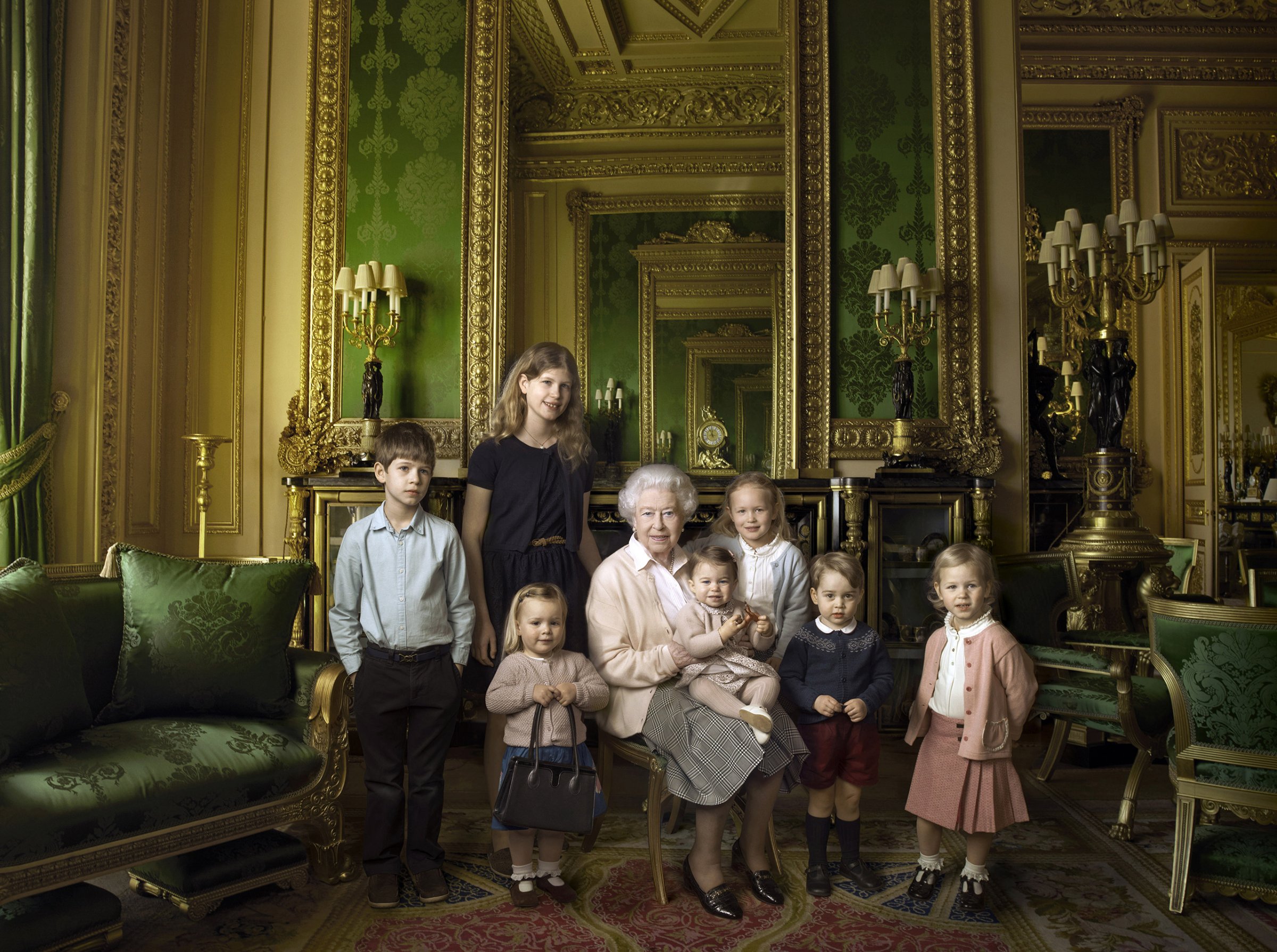 This official photograph released by Buckingham Palace to mark Queen Elizabeth II's 90th birthday shows her five great-grandchildren and her two youngest grandchildren in the Green Drawing Room, part of Windsor Castle's semi-State apartments, April 20, 2016. The children are: James Viscount Severn (left), 8, and Lady Louise Windsor (second left), 12, the children of The Earl and Sophie Countess of Wessex; Mia Grace Tindall (holding The Queen's handbag), the two year-old-daughter of Zara and Mike Tindall; Savannah (third right), 5, and Isla Phillips (right), 3, daughters of The Queen's eldest grandson Peter Phillips and his wife Autumn; Prince George (second right), 2, and in The Queen's arms and in the tradition of Royal portraiture, the youngest great-grandchild, Princess Charlotte of Cambridge, 11 months), children of Prince William and Catherine Duchess of Cambridge.