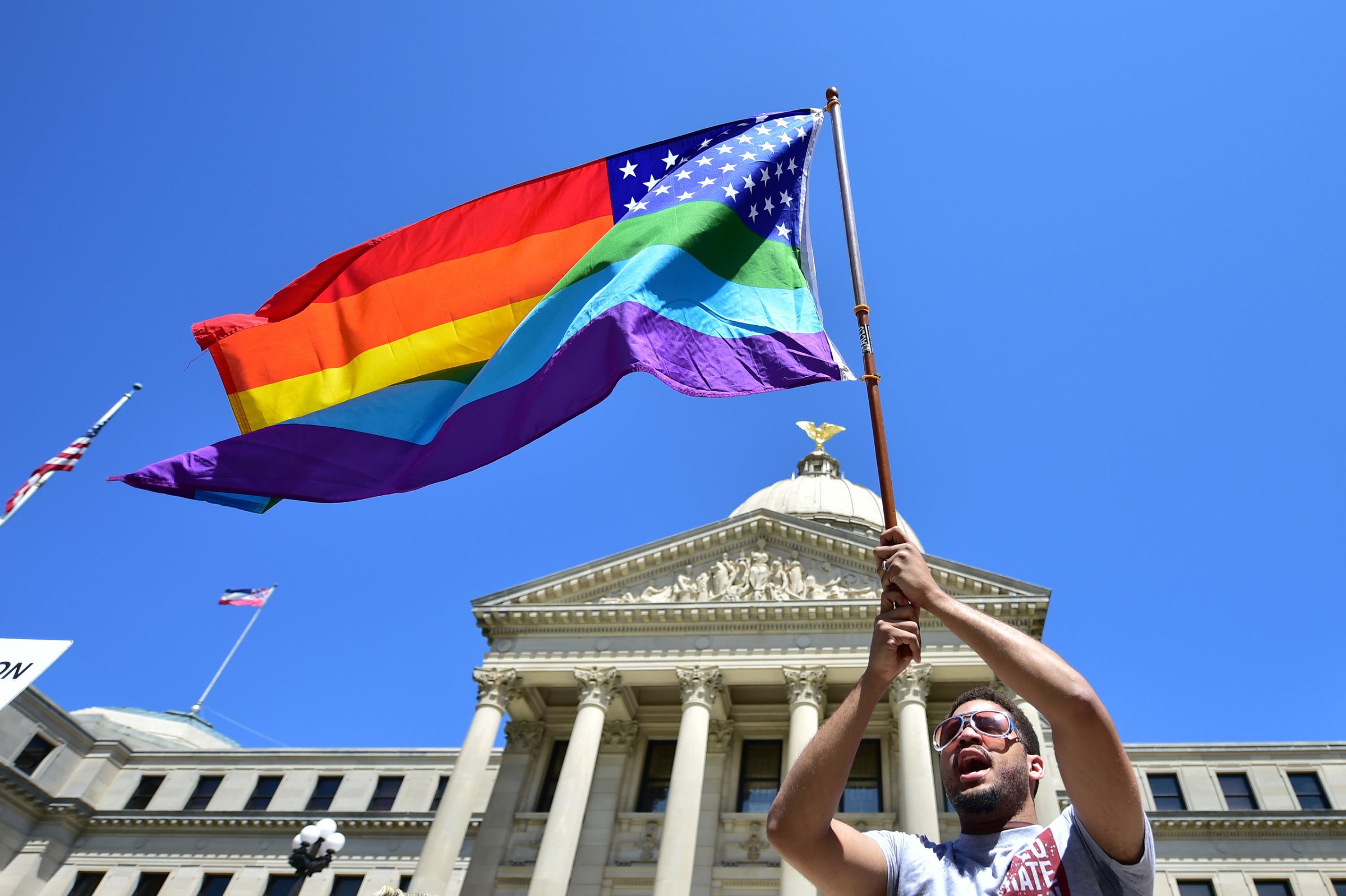 Meridian resident Nykolas Alford waves a rainbow-colored flag designed with the U.S. flag during a Human Rights Campaign protest of House Bill 1523 on the Mississippi State Capitol steps in Jackson, Miss., Tuesday, March 29, 2016. (Justin Sellers/The Clarion-Ledger via AP) MANDATORY CREDIT
