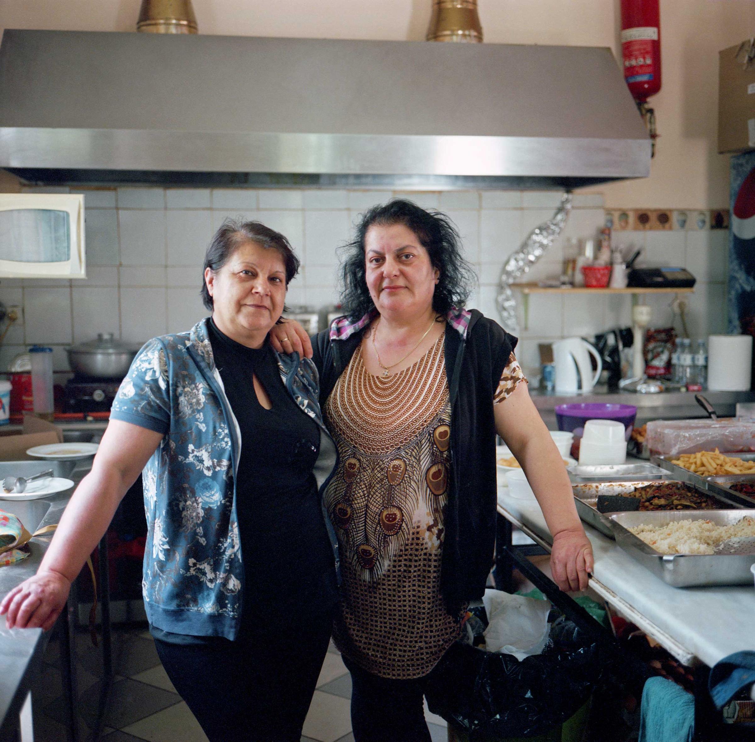 Nopi Pantelidou (left) and Gianna Konstantinidou work in the kitchen at a cafe in Idomeni. A small canteen that used to serve local residents and others passing through the Idomeni train station is now overflown with refugees. They come here to charge their phones and tablets and use the free WiFi. Some can afford a meal, but most pass their time playing cards, smoking and making calls to relatives abroad. Idomeni, Greece, April 2016