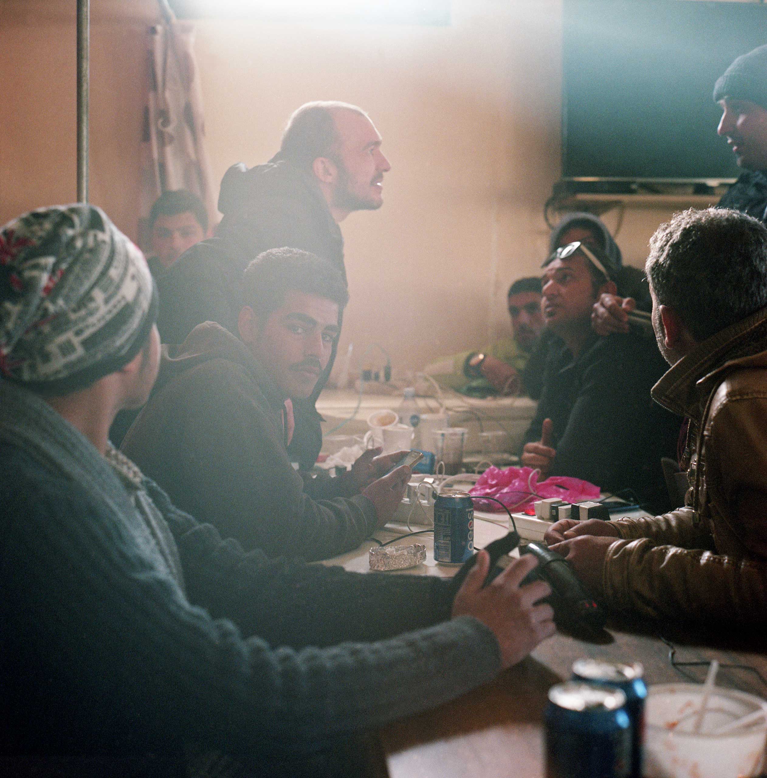 In the small canteen, refugees come to charge their phones and tablets and use the free WiFi. Some can afford a meal, but most pass their time playing cards, smoking and making calls to relatives abroad. Idomeni, Greece, April 2016