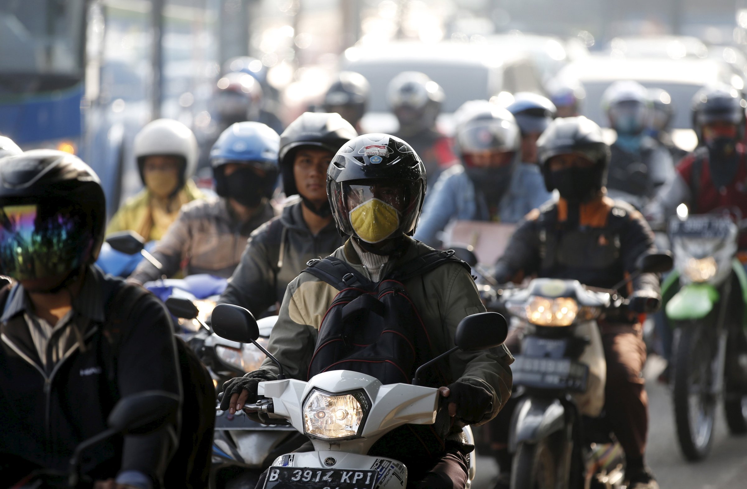 Motorcyclists ride on a major route next to a toll road into Jakarta