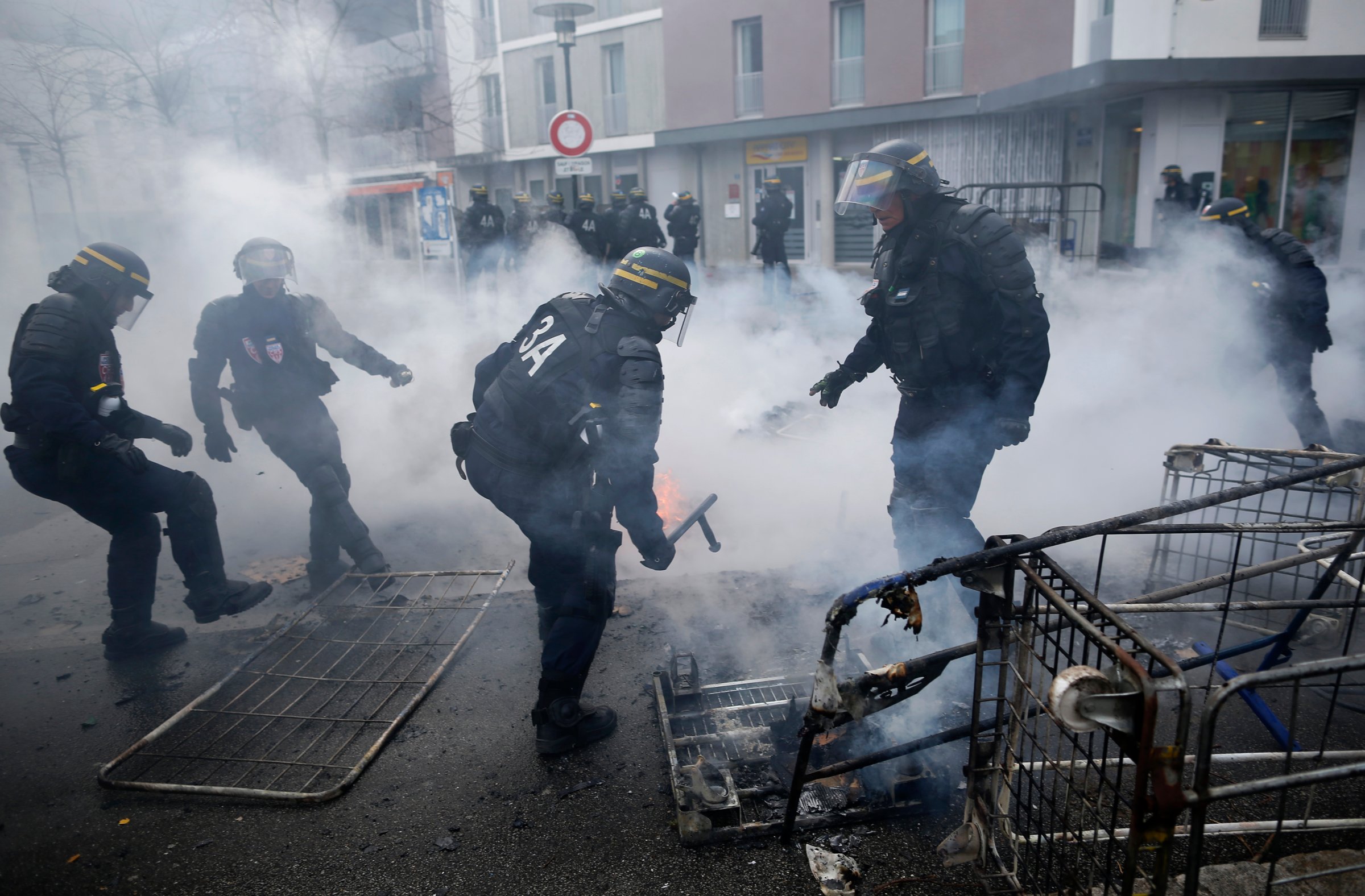 French gendarmes clean debris after youths set fire to garbage bins and caddies as French high school and university students attend a demonstration against the French labour law proposal in Nantes