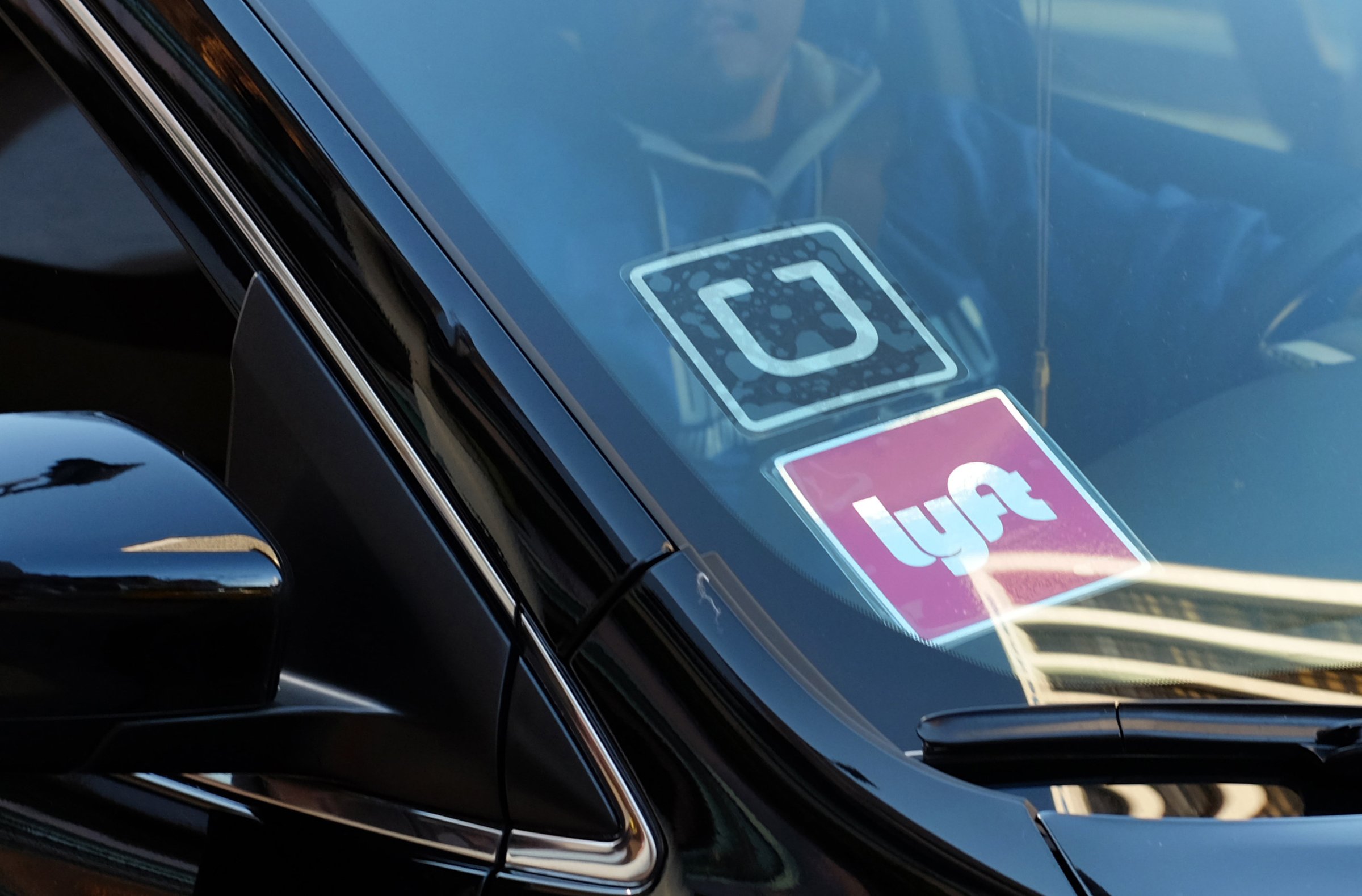 Los Angeles Lyft and UberA driver displaying Lyft and Uber stickers on his front windshield drops off a fare in downtown Los Angeles, Calif on Jan. 12, 2016.