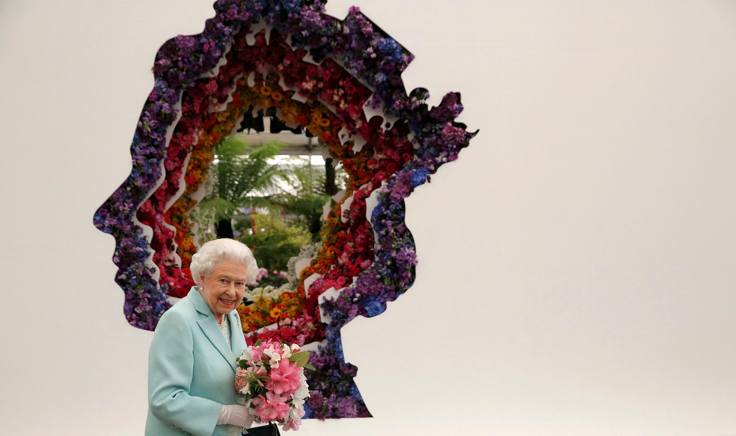 Queen Elizabeth II stands in front of a floral exhibit by the New Covent Garden Flower Market, which features an image of the Queen at the Chelsea Flower Show in London, May 23, 2016.