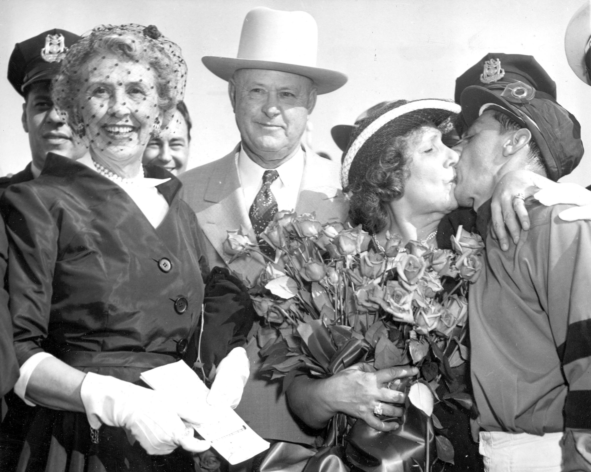 Jockey Eddie Arcaro is kissed by his mother, Josephine, holding roses, after winning the Kentucky Derby at Churchill Downs, Louisville, Ky., on May 3, 1952. At left is Lucille Parker Wright, whose racing stable Calumet Farm has had five Derby winners. At center is Ben Jones, who has trained all six Derby winners.