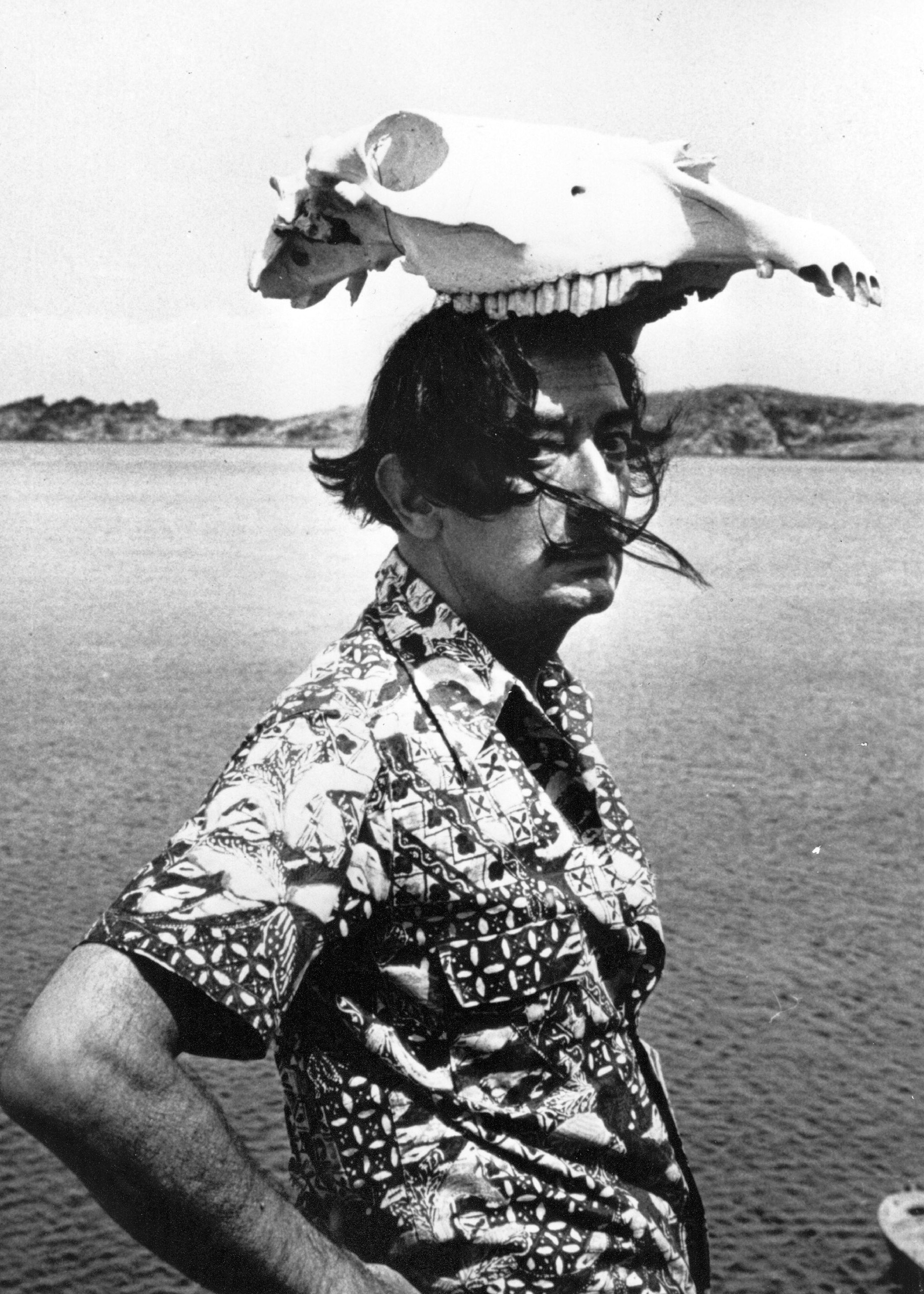 Salvador Dali wearing an animal skull as a hat. 1950.