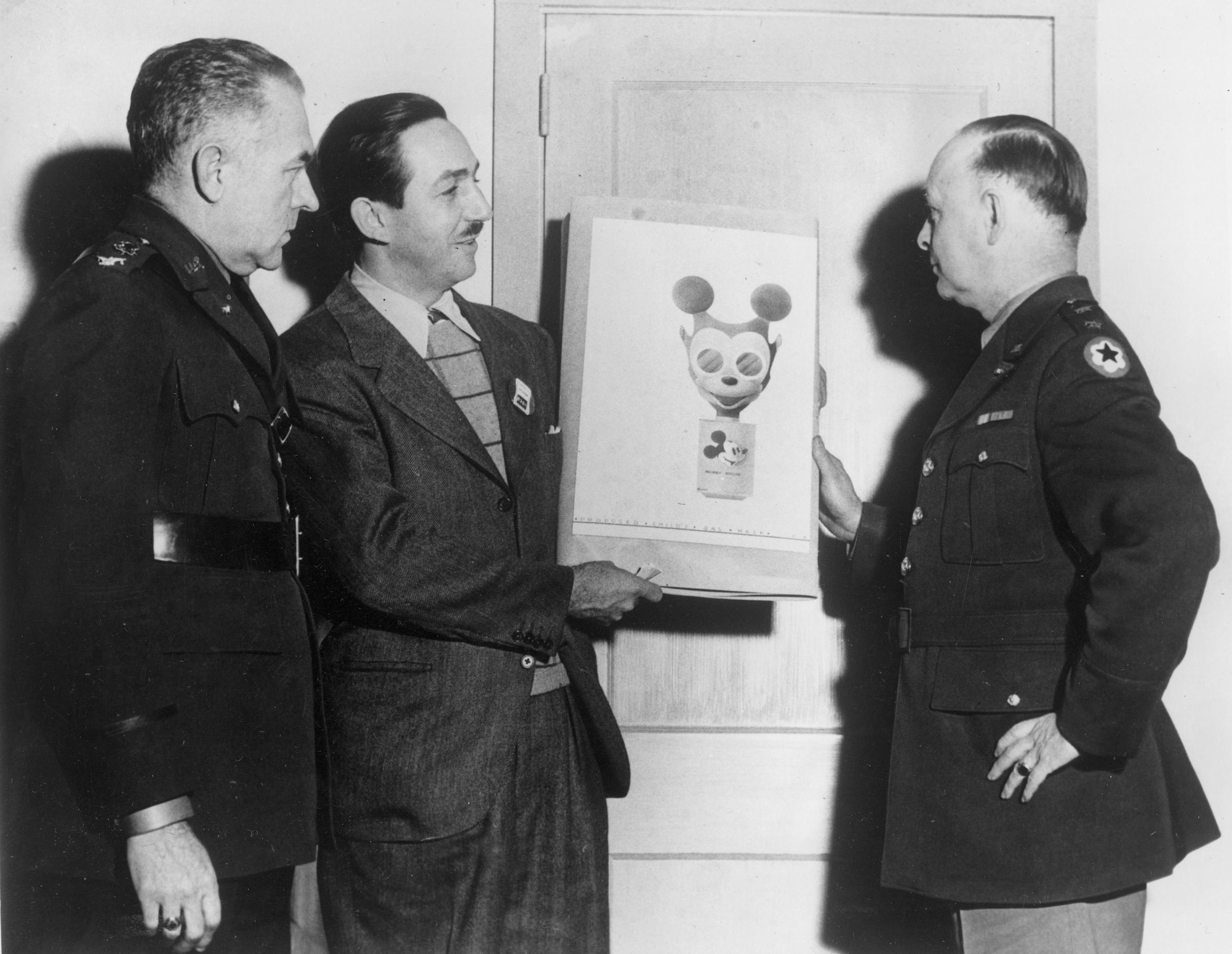 Animator Walt Disney, second from left, hands over his sketch of a Mickey Mouse gas mask to Maj. Gen. William Porter, right, in Washington, D.C., Jan. 8, 1942. Civilian defense and chemical warfare officers plan to produce the design intended to encourage children to use their mask readily for protection during World War II.