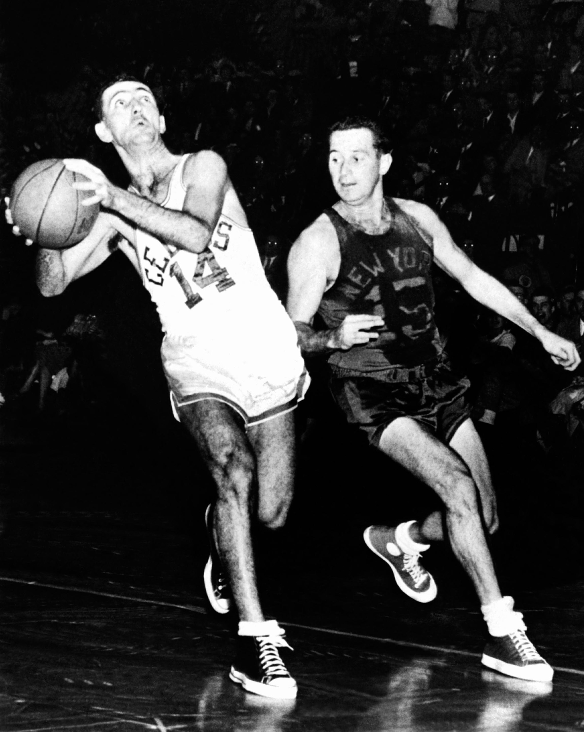 Bob Cousy #14 of the Boston Celtics drives to the basket against Dick McGuire #15 of the New York Knicks at the Boston Garden circa 1950 in Boston, Massachusetts.