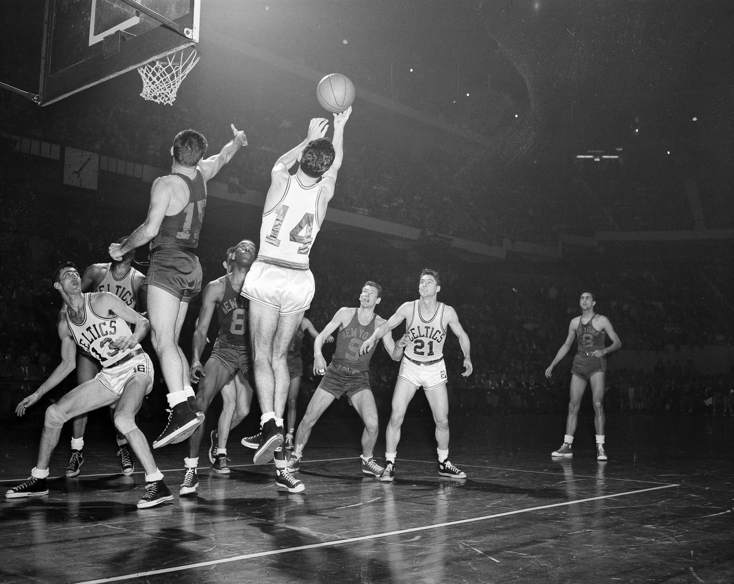 Bob Cousy (14) of the Boston Celtics takes a rebound off the backboard after an attempted basket by Dick McGuire (15) of the New York Knickerbockers in the fourth quarter of their NBA playoff game at the Boston Garden in Boston, Mass., March 26, 1953.