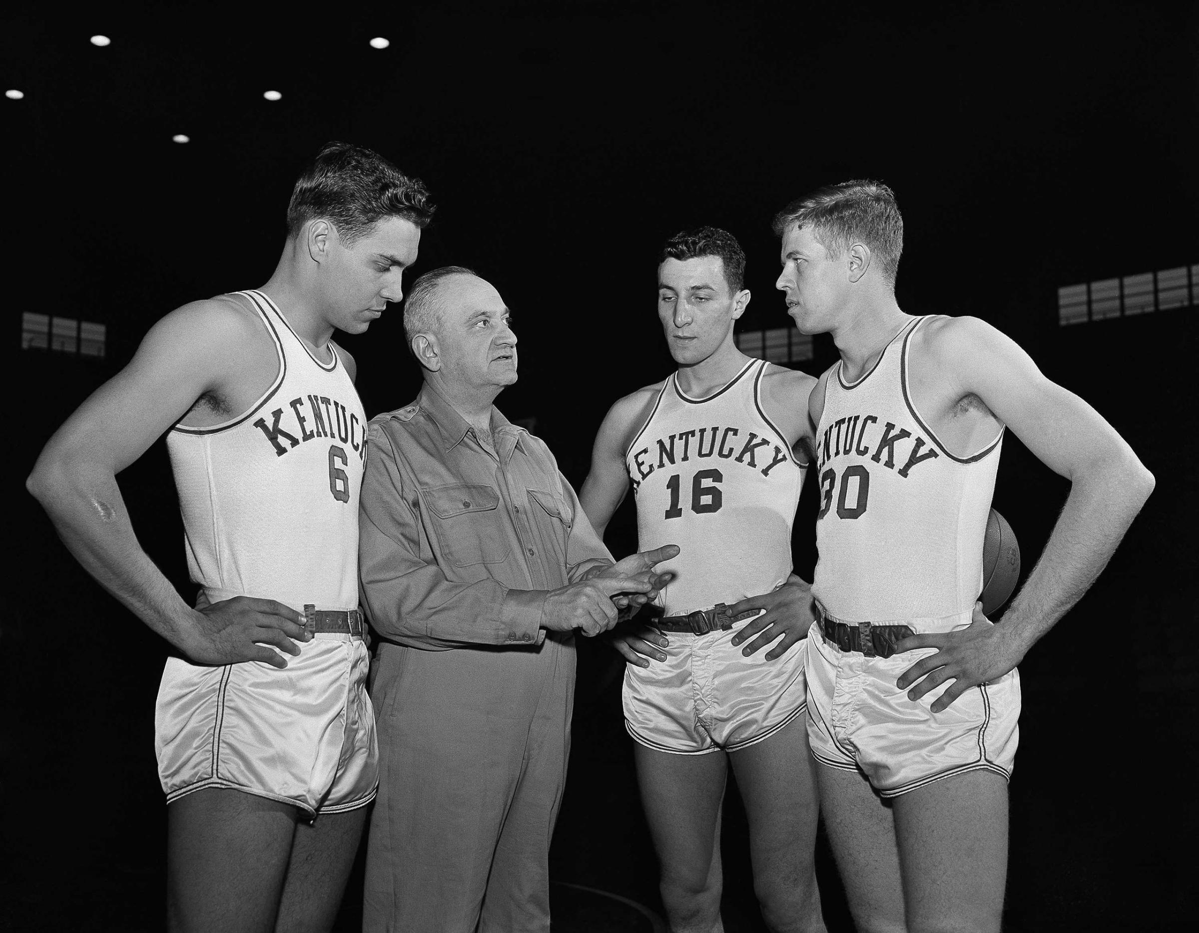 Kentucky basketball coach Adolph Rupp talks to players, from left, Cliff Hagan, Lou Tsioropoulos and Frank Ramsey (30) in Lexington, Ky. Circa 1954.