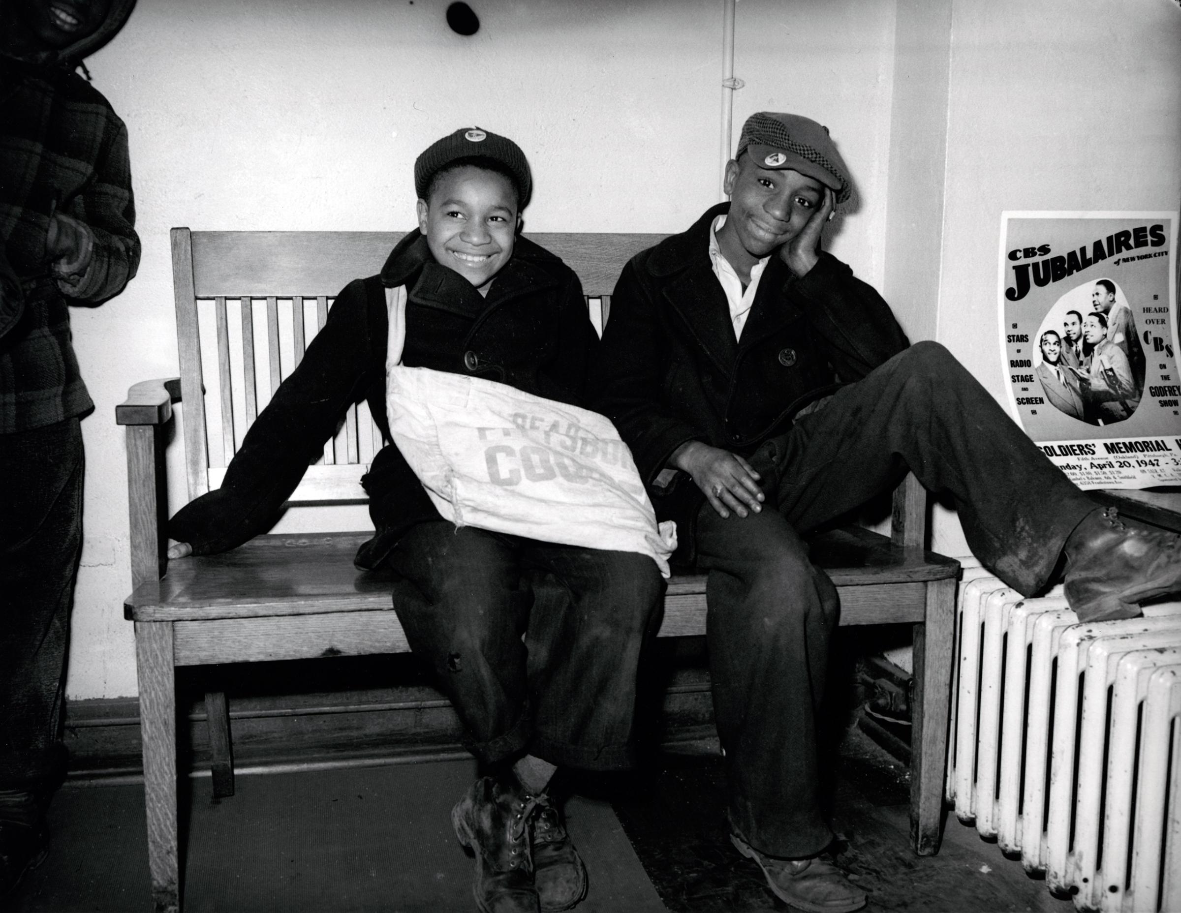 Two paper boys sitting on a bench, 1947.