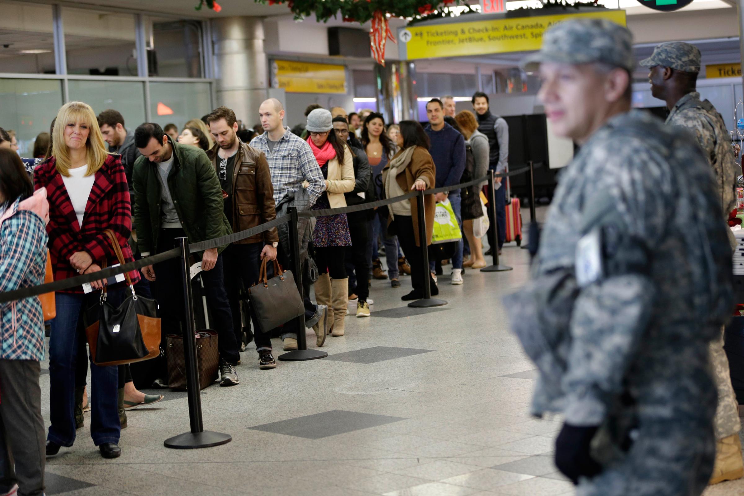 Security personnel looks on as passengers wait to pass through airline security at LaGuardia Airport in New York, Wednesday, Nov. 25, 2015. An expanded version of America's annual Thanksgiving travel saga was under way Wednesday with gas prices low and terrorism fears high. An estimated 46.9 million Americans are expected to take a car, plane, bus or train at least 50 miles from home over the long holiday weekend, according to the motoring organization AAA. That would be an increase of more than 300,000 people over last year, and the most travelers since 2007. (AP Photo/Seth Wenig)