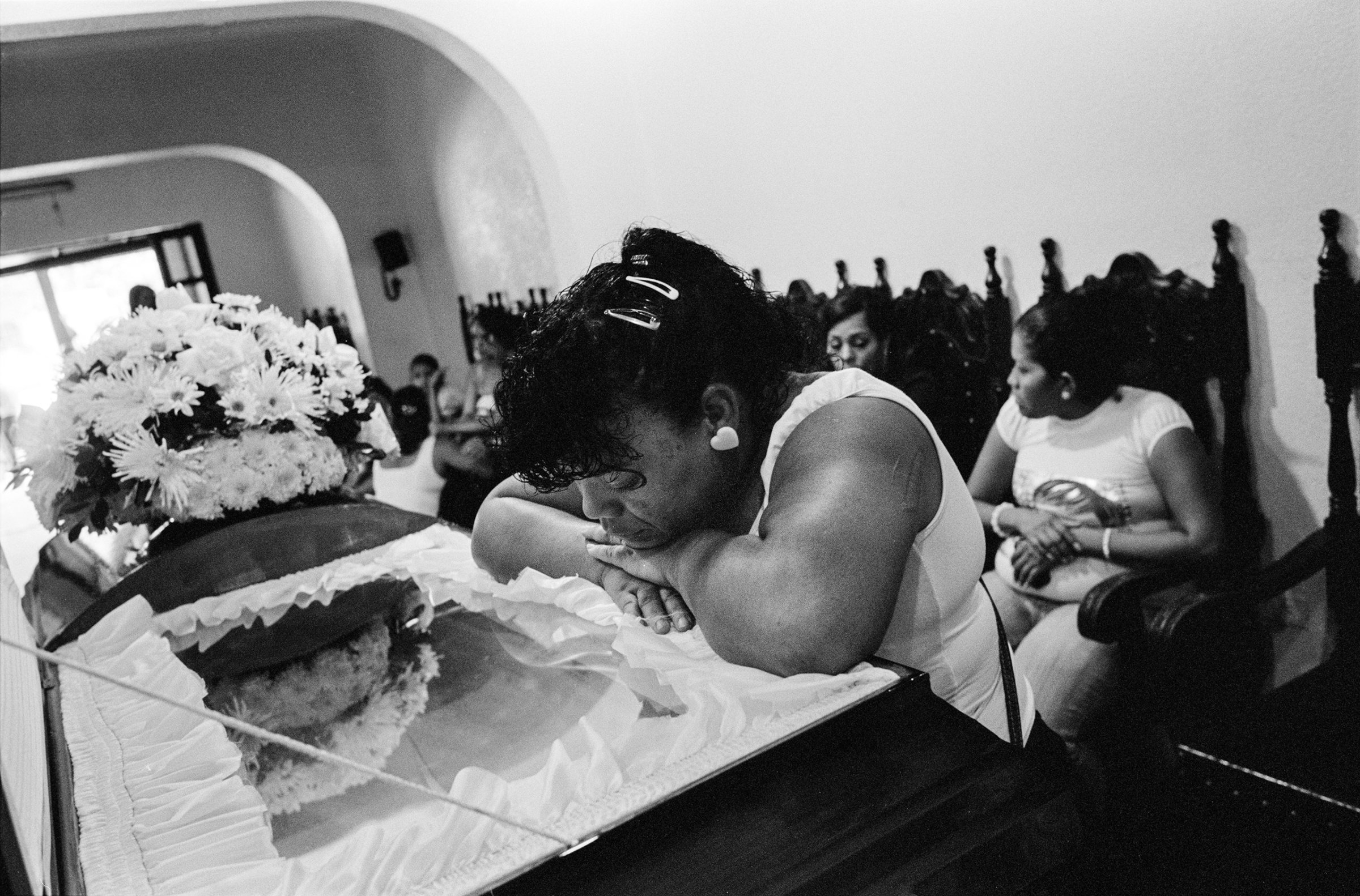 A family mourns at the funeral of a man who was shot dead with 16 bullets to the head, while coming out of his home with his daughter, by one of the "colectivos" of Caracas, November 2009. He was part of a rival gang.