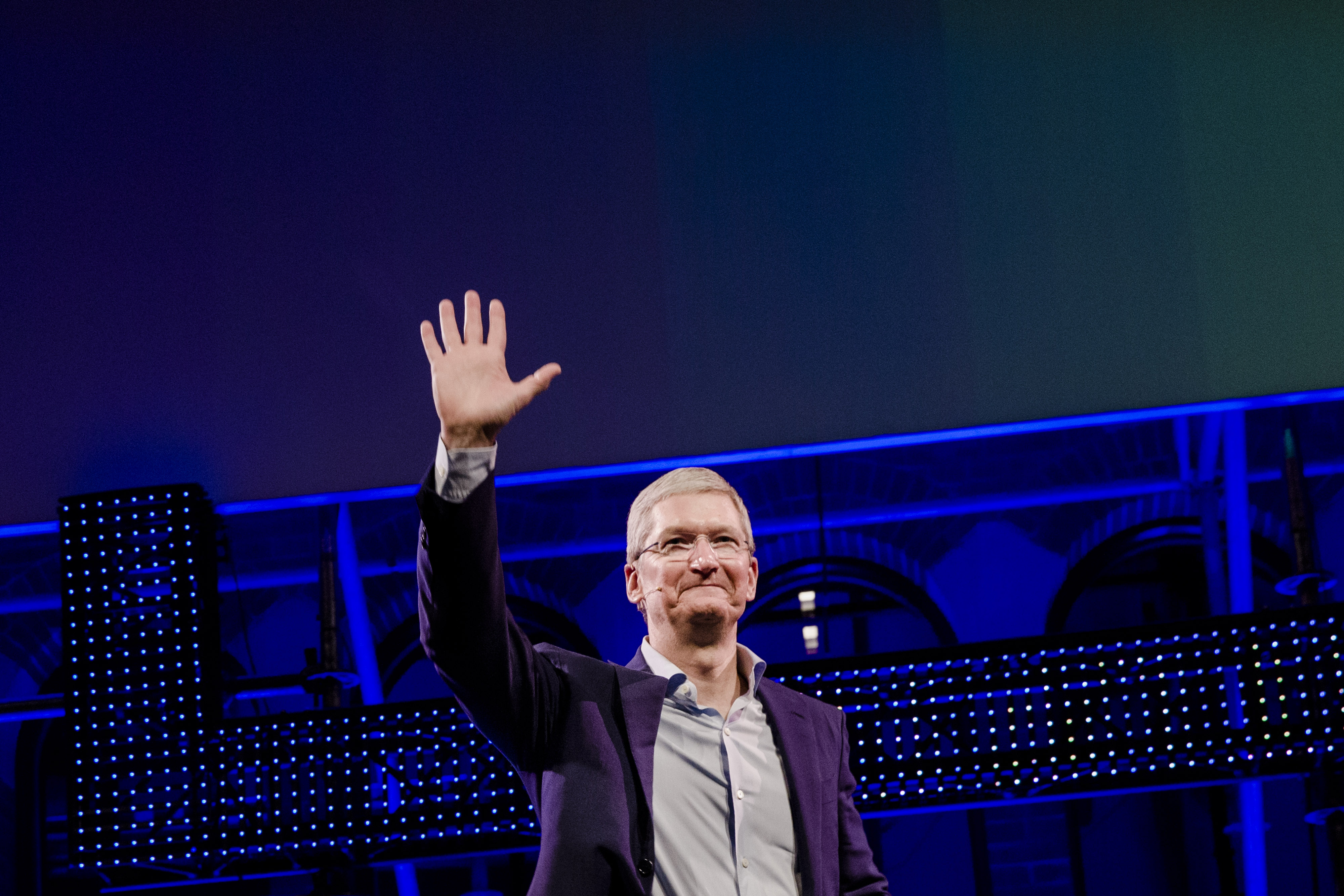 Tim Cook, chief executive officer of Apple Inc., waves to the audience during the opening of 