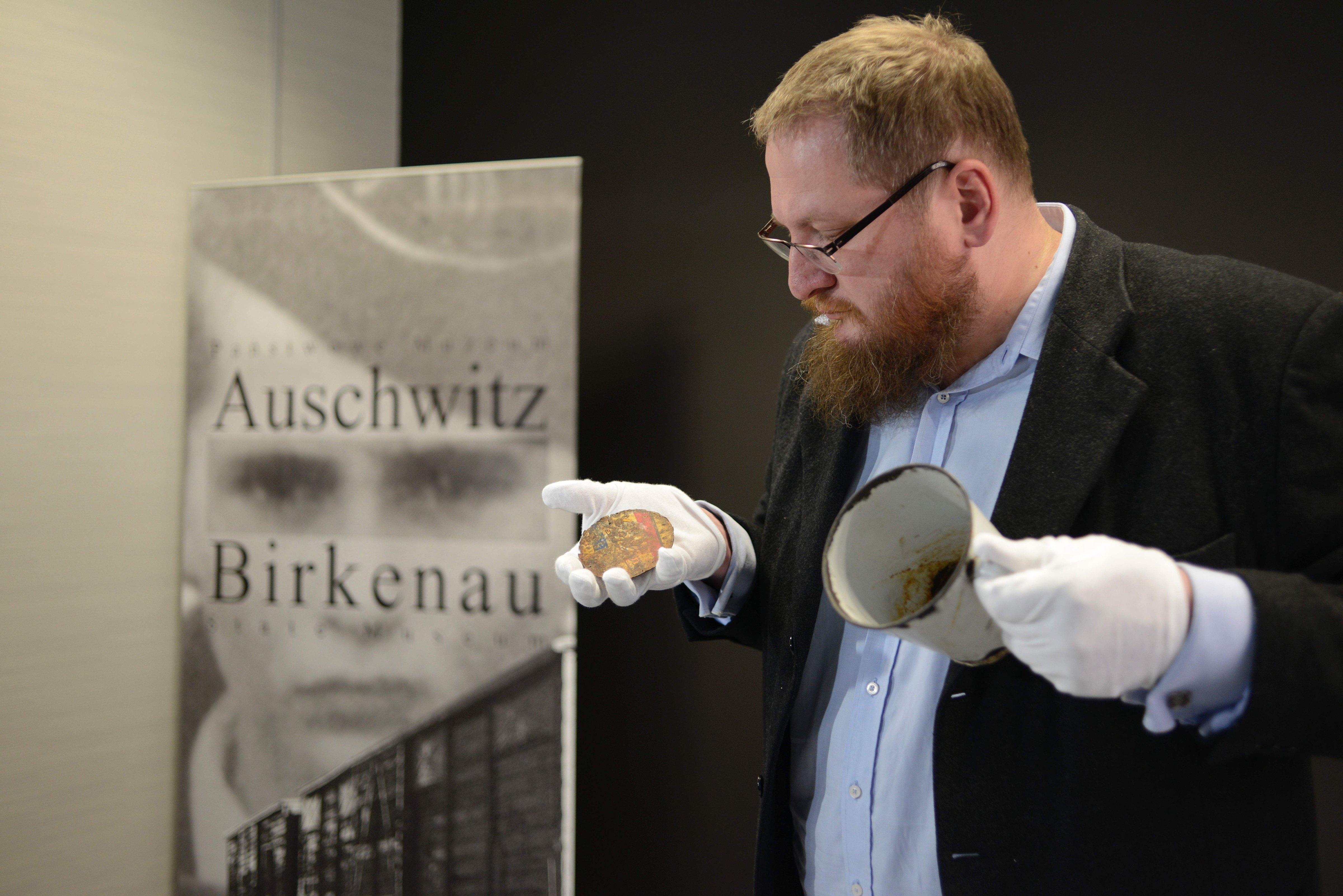 Piotr Cywinski, director of the Auschwitz-Birkenau museum, presents a metal mug with a double bottom in which a gold ring and necklace were found by employees of the museum in Oswiecim, Poland, May 19, 2016. (Bartosz Siedlik—AFP/Getty Images)