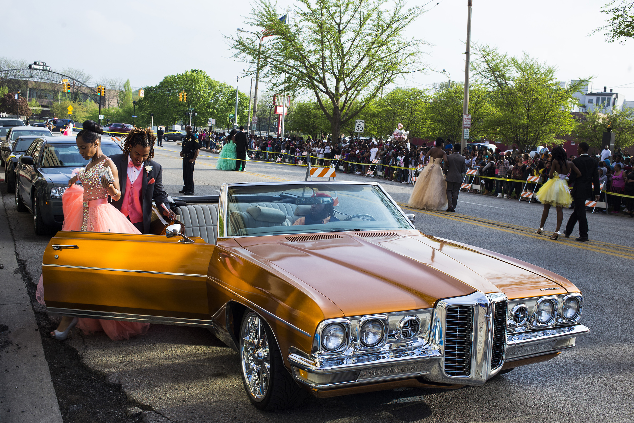 Flint Southwestern Classical Academy senior Reyna Deloney exits a car along with her date, Johnanthony Fulgham, while getting dropped off at their prom in downtown Flint, May 2015. Members of the community lined the closed-down street to cheer and take pictures.