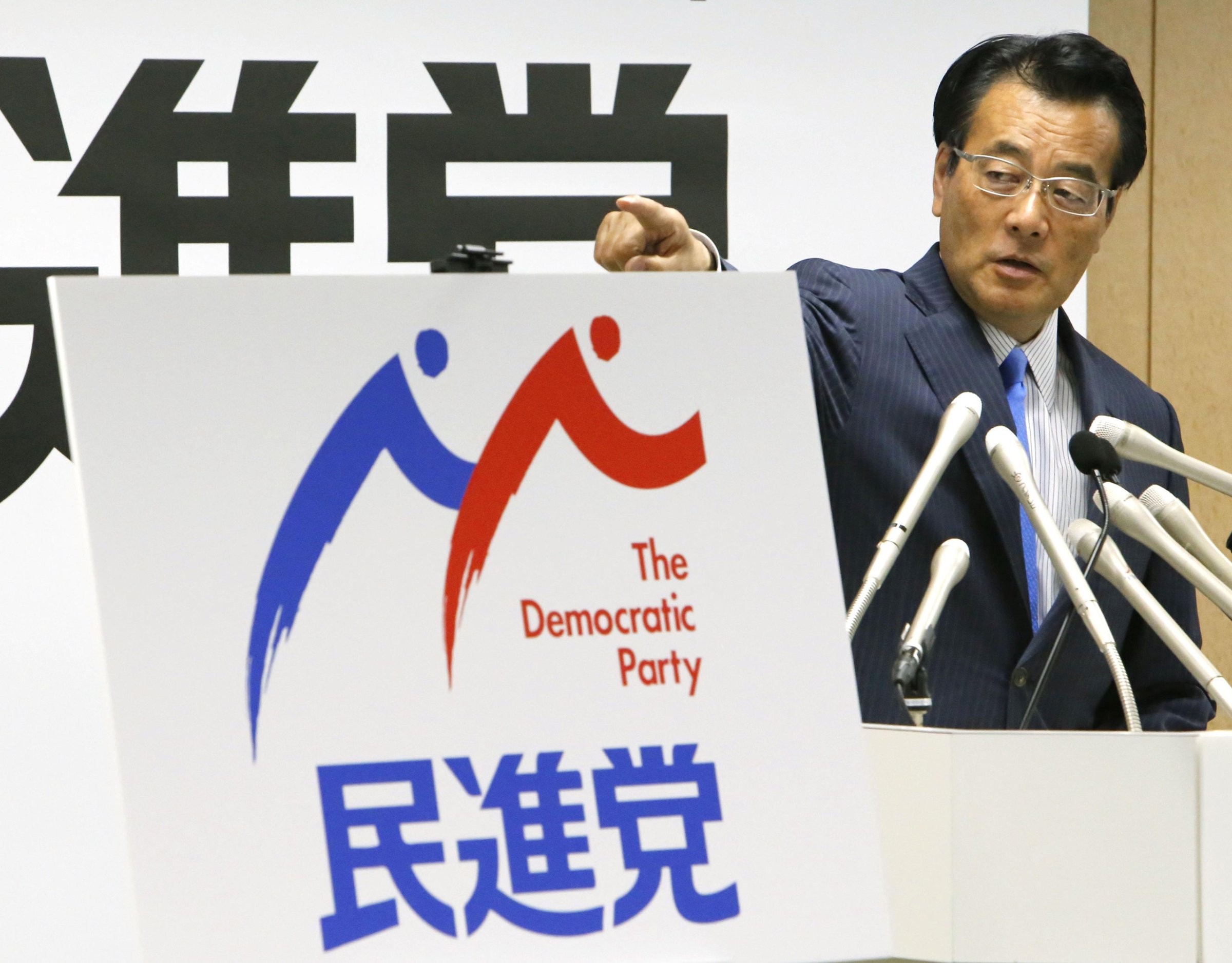 Katsuya Okada, leader of the main opposition Democratic Party, unveils the party's logo at a press conference in Tokyo on May 19, 2016.