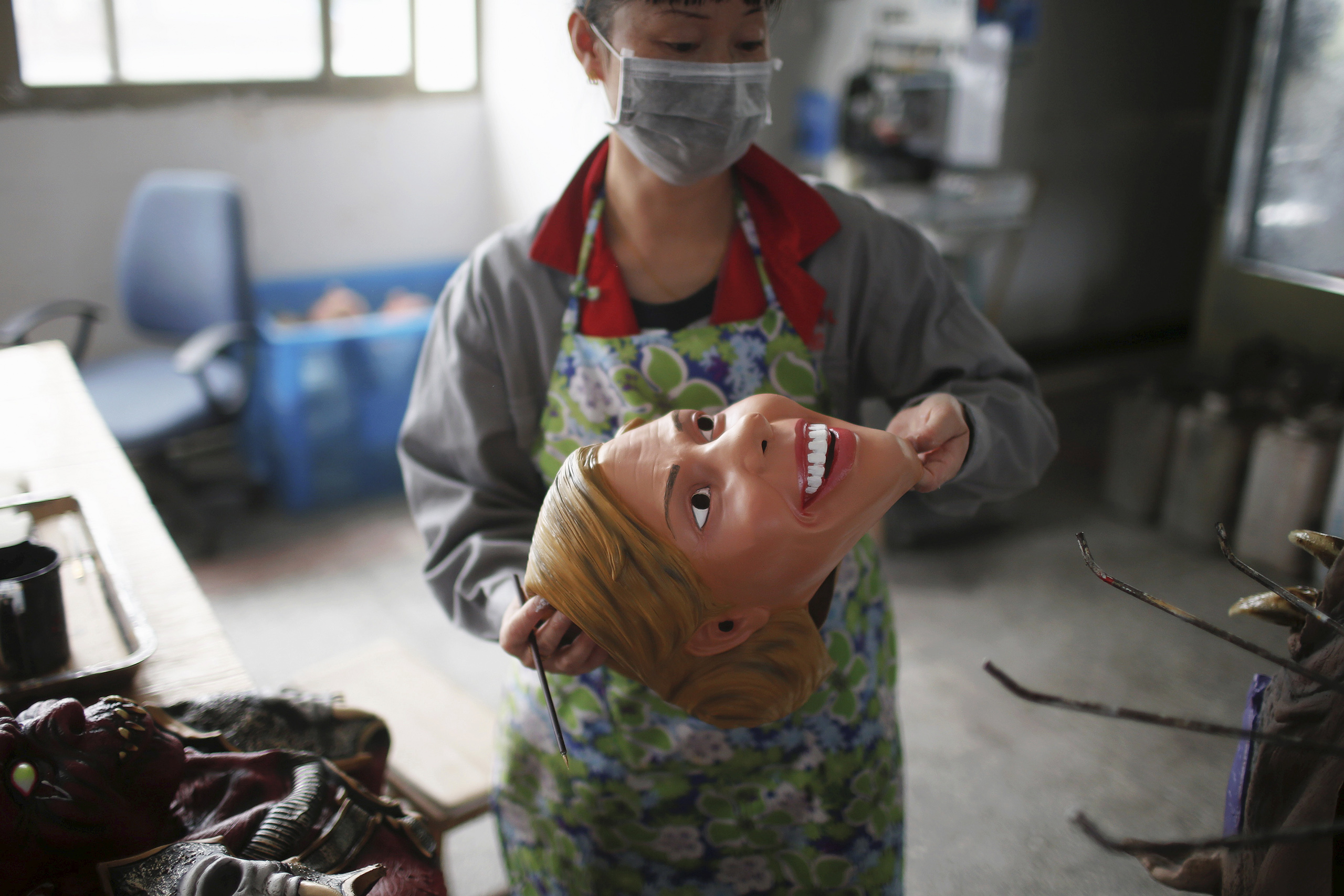 A worker checks a mask of Democratic presidential candidate Hillary Clinton, which was just painted, at Jinhua Partytime Latex Art and Crafts Factory in Jinhua, Zhejiang Province, China, May 25, 2016.