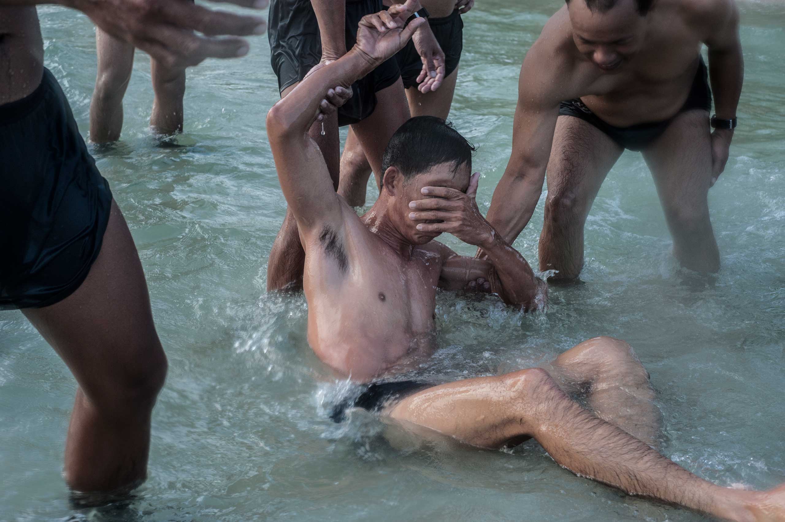 Heang Sambo, 38, collapses during an intense training session on the beach at Sihanoukville, Cambodia in April 2013. At the beginning of the training, many of the now divers could not swim. Now divers swim regularly and conduct daily physical training. Sambo, who is not a full-time member of the team but trains alongside them, works as a detection specialist and has worked all over the world identifying UXO.