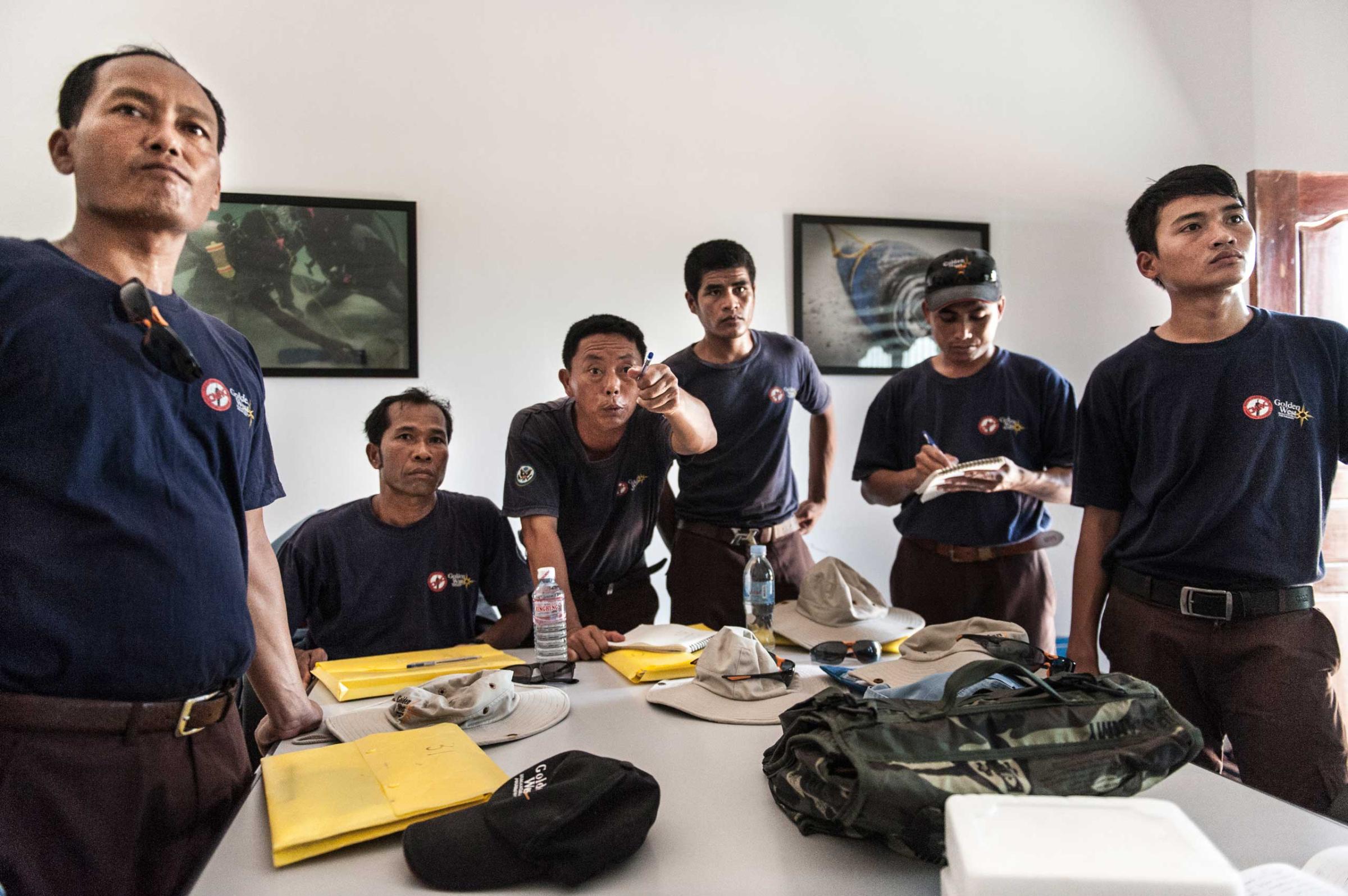 Members of the UXO salvage dive team take part in a mission brief in their dive shop in Kampong Chhanang, Cambodia in Sept. 2014.