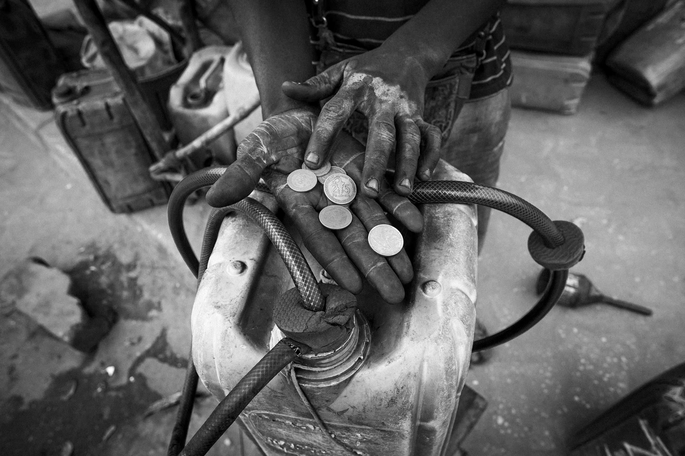 A child counting the benefits of the petrol sale. Women and children are responsible for selling in exchange for low salaries, but which complement the economy of a home in which all of its members carry out a duty in the chain.