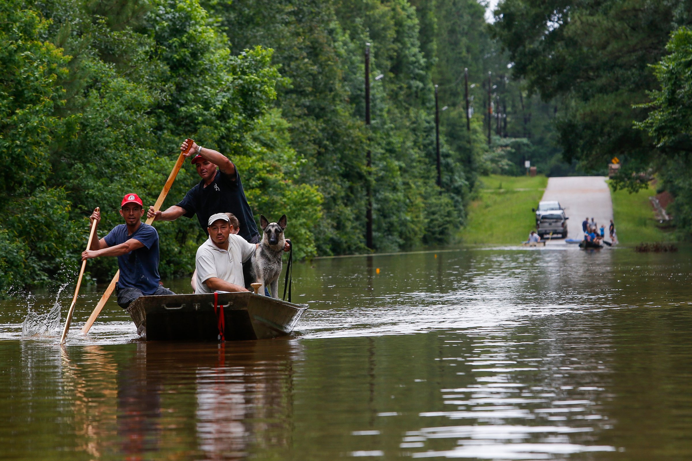Roland Courville steers a boat across Mill Creek Road as he helps people escape from a neighborhood cut off by a flooded Spring Creek in Magnolia, Tex. on May 27, 2016, (Michael Ciaglo/Houston Chronicle via AP) MANDATORY CREDIT