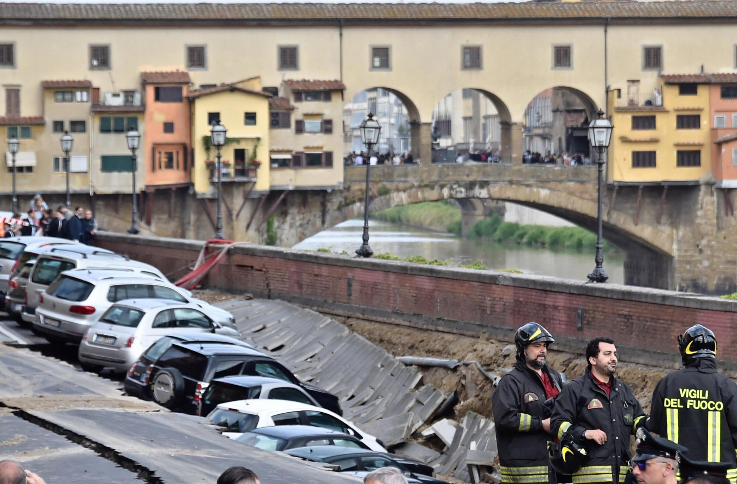 Firefighters standby by cars engulfed by a chasm which opened along Arno river near the Ponte Vecchio Old Bridge in Florence, Italy, on May 25, 2016. (Maurizio degl'Innocenti—ANSA/AP)