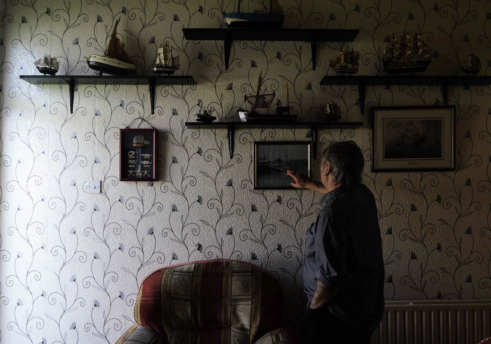 Retired fisherman Peter Cole, 62, points to an old photograph of the local docks at his home in Grimsby, U.K., on May 27, 2016.