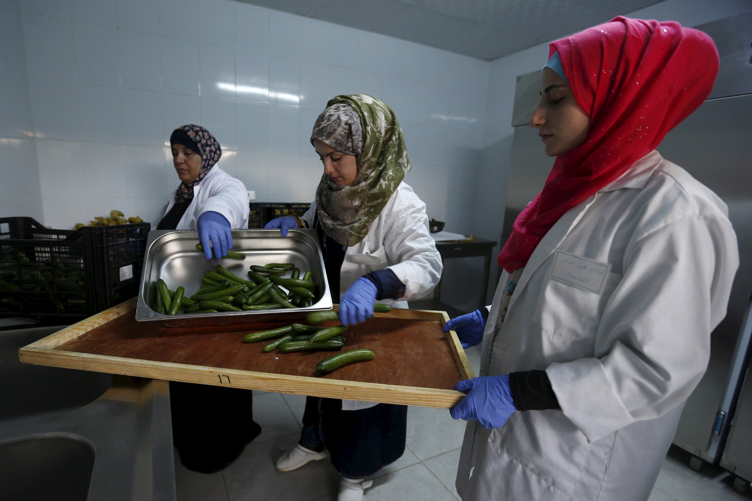 Workers prepare meals for students as part of a World Food Programme (WFP)-run project to provide healthy meals to students and to raise awareness of good eating habits, in the city of Irbid, Jordan, April 26, 2016. REUTERS/ Muhammad Hamed - RTX2BQN2