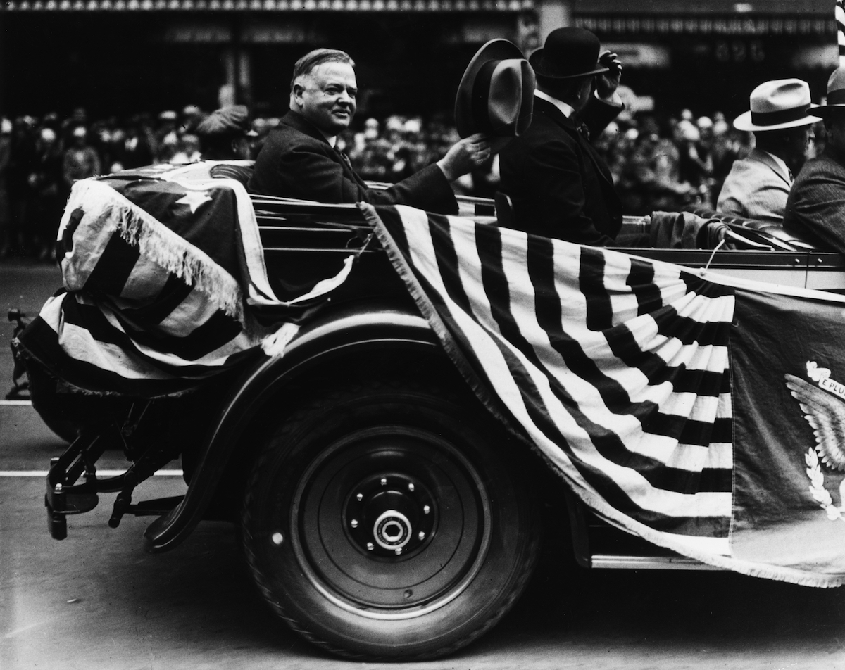 US president Herbert Hoover waves his hat in recognition of the crowds surrounding his car in a parade, San Francisco, Aug. 26, 1928 (American Stock Archive / Getty Images)