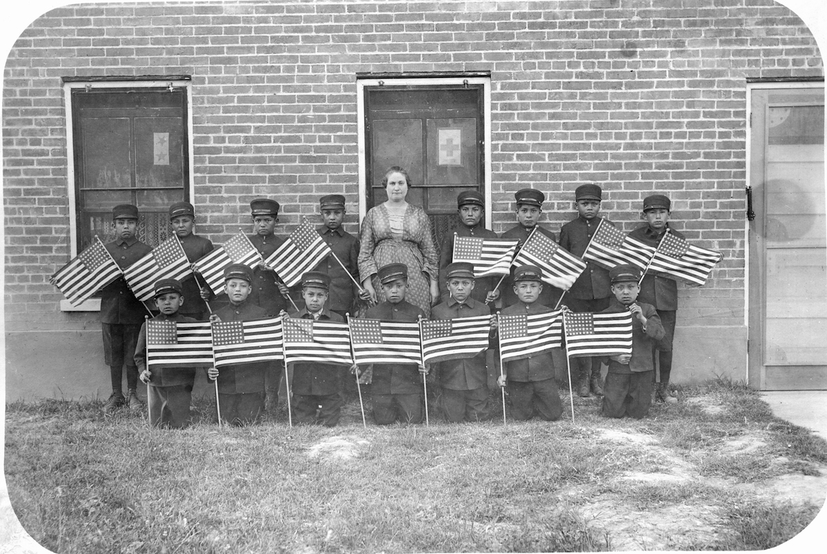 View of students and their teacher from the Albuquerque Indian School, late 1890s or early 1900s. Boys holding American flags. (PhotoQuest / Getty Images)