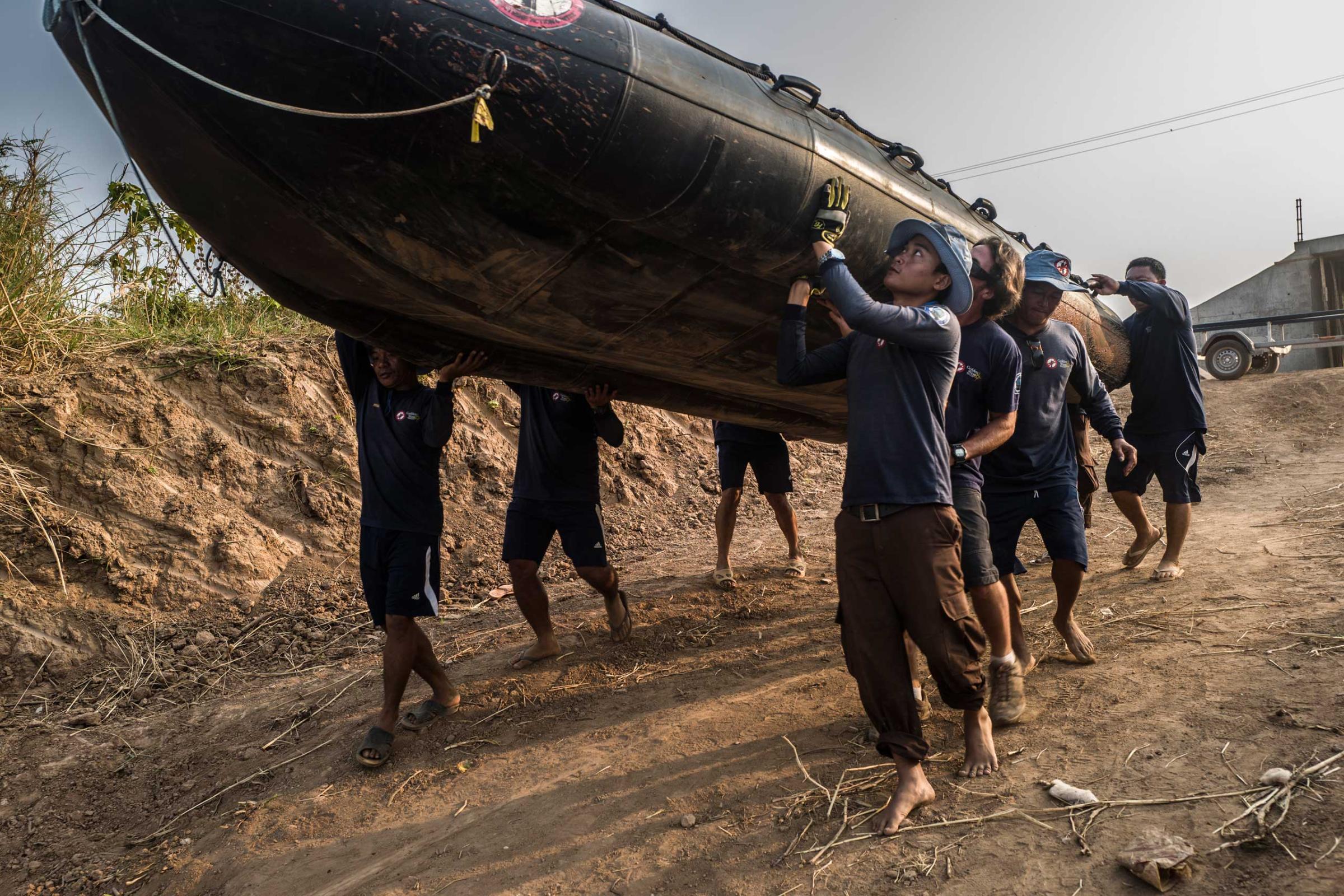 The diver team carries an inflatable boat down the banks of the Tonle Sap river in March 2016.