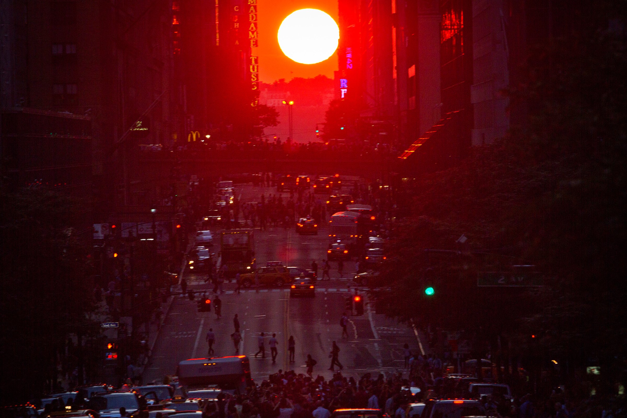 People crowd onto 42nd Street as they take photos of the "Manhattanhenge" phenomenon in the Manhattan borough of New York July 11, 2014. Manhattanhenge, coined by astrophysicist Neil deGrasse Tyson, occurs twice a year, when the setting sun aligns itself with the east-west grid of streets in Manhattan. REUTERS/Carlo Allegri (UNITED STATES - Tags: SOCIETY TPX IMAGES OF THE DAY) - RTR3Y8KN