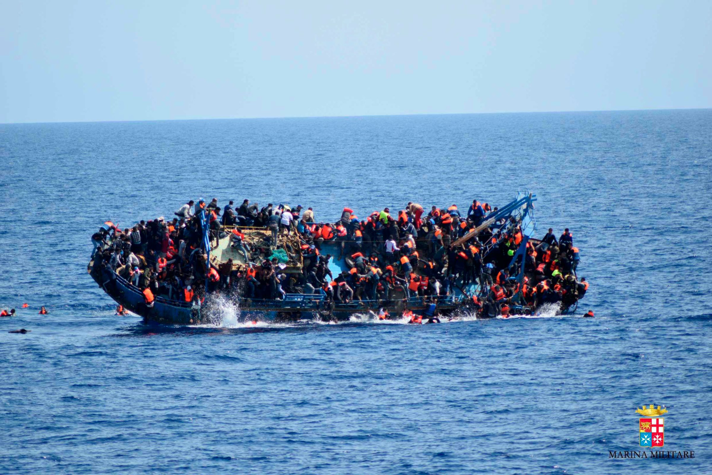 TOPSHOT - This handout picture released on May 25, 2016 by the Italian Navy (Marina Militare) shows the shipwreck of an overcrowded boat of migrants off the Libyan coast today. At least seven migrants have drowned after the heavily overcrowded boat they were sailing on overturned, the Italian navy said. The navy said 500 people had been pulled to safety and seven bodies recovered, but rescue operations were continuing and the death toll could rise. The navy's Bettica patrol boat spotted "a boat in precarious conditions off the coast of Libya with numerous migrants aboard," it said in a statement.