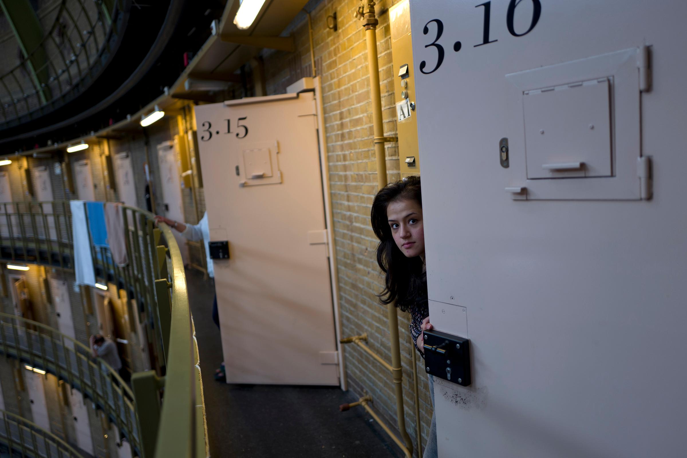 Afghan refugee Shazia Lutfi, 19, peeks through the door of her room at the former prison of De Koepel in Haarlem, Netherlands, May 7, 2016.